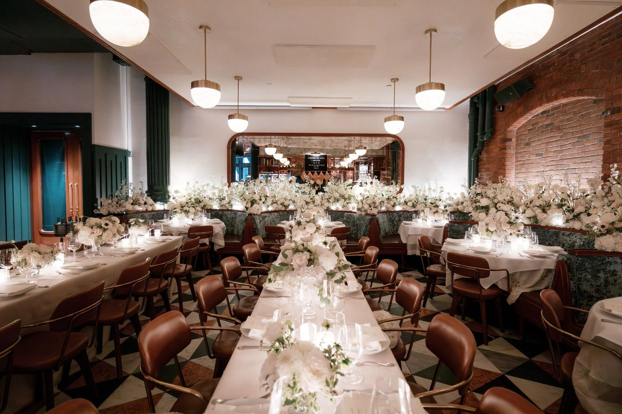 Elegant long banquet tables lined with white florals and candlelight inside Torrisi in Manhattan, photographed by Jenny Fu.