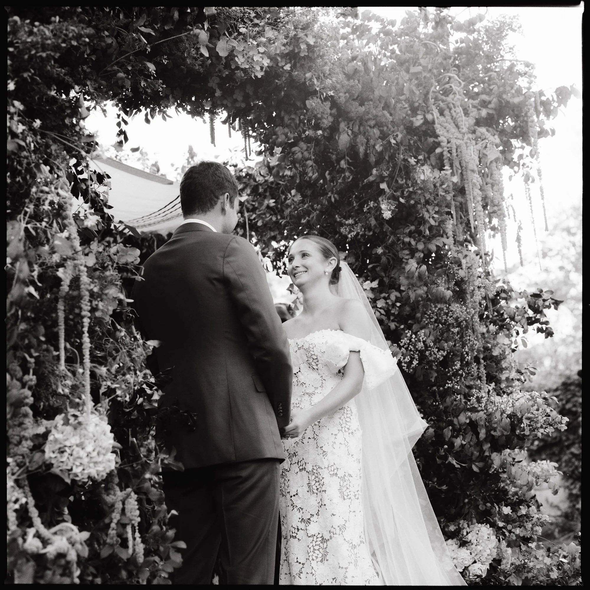 Bride and groom sharing vows in golden light surrounded by florals during their ceremony at Troutbeck in Amenia, photographed by Jenny Fu.
