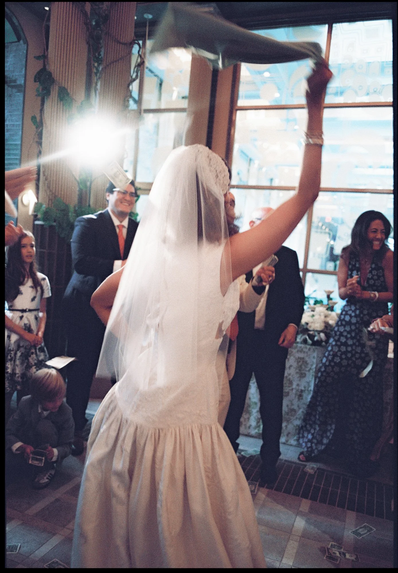 Bride in her veil waving a napkin overhead as guests dance at her Waldorf Astoria New York wedding reception, photographed by Jenny Fu.
