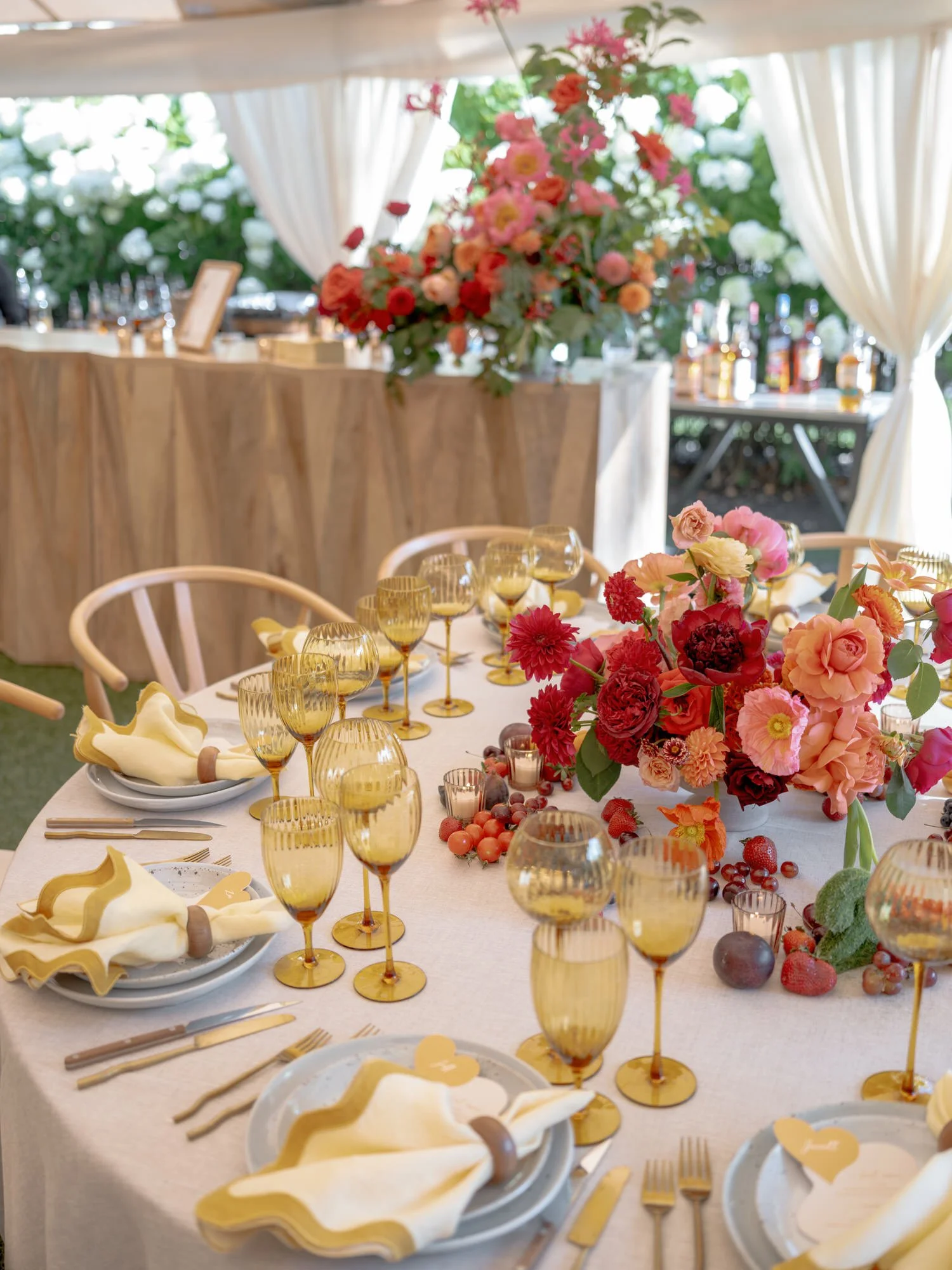 Colorful reception table set with yellow glassware and bright red florals inside the tented celebration at Valley Rock Inn in Sloatsburg, photographed by Jenny Fu.