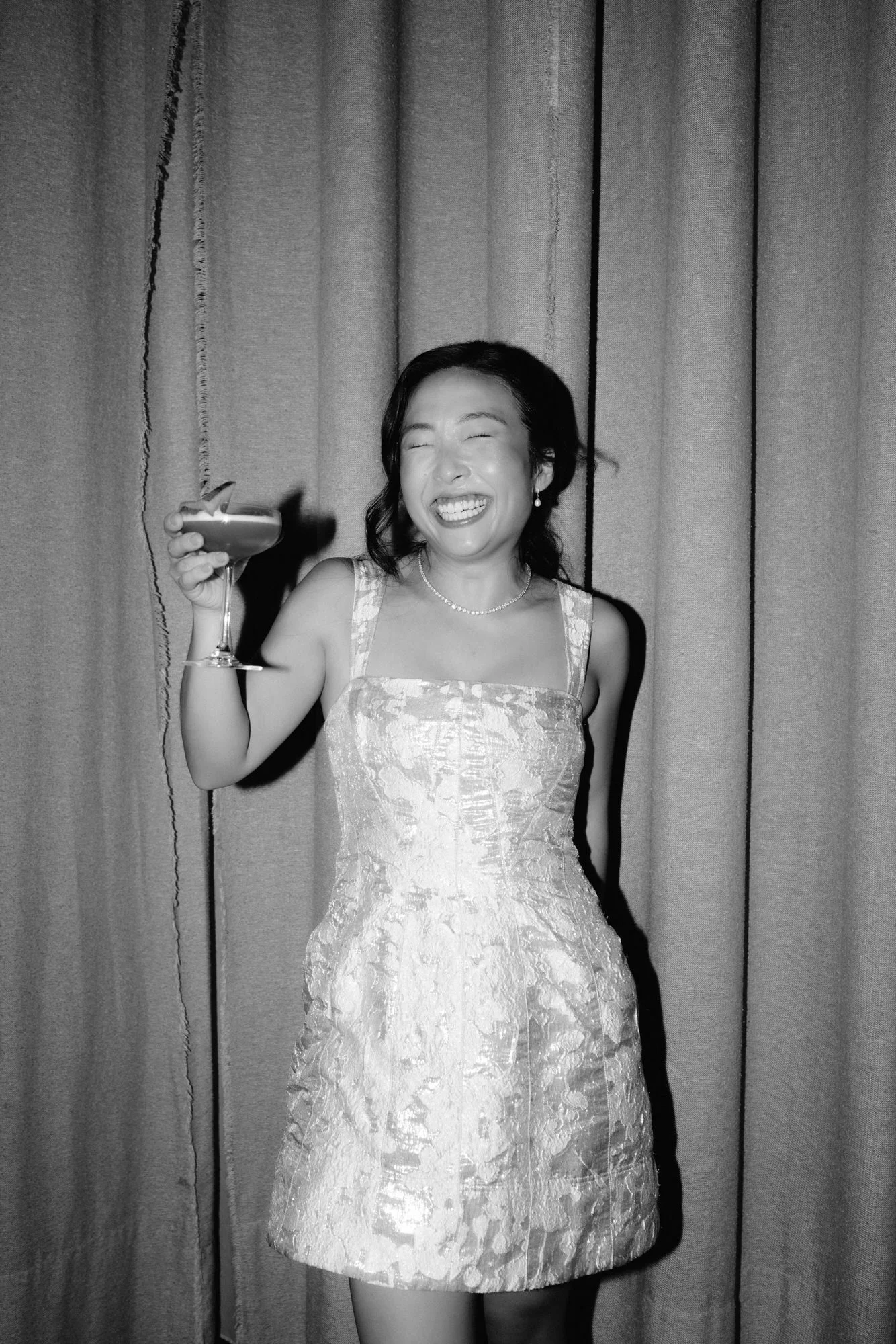 Bride in a silver mini dress holding a cocktail in black and white at Blue Hill at Stone Barns, photographed by Jenny Fu.