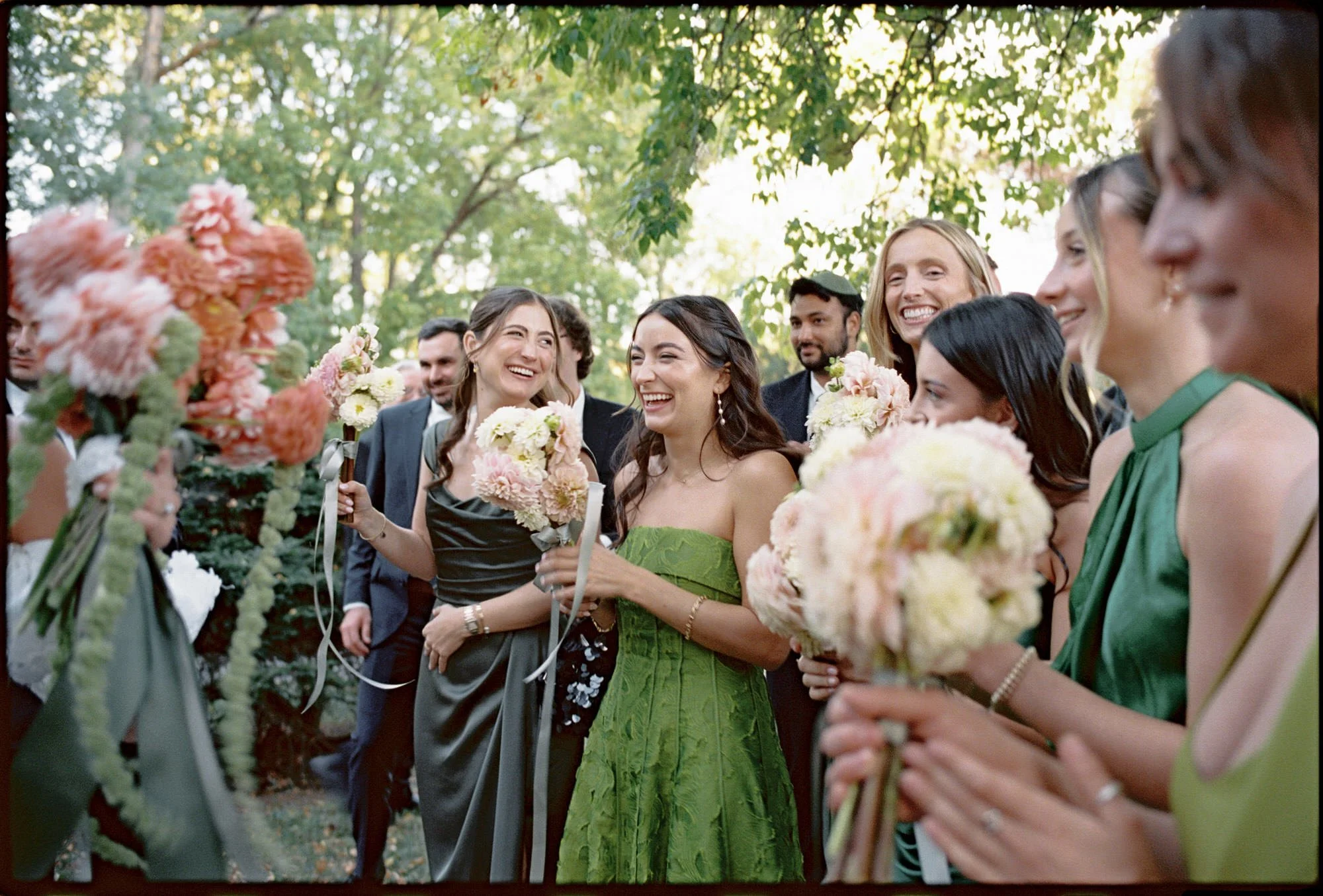 Bridesmaids laughing and holding blush bouquets beneath maples at Troutbeck in Amenia, New York, photographed by Jenny Fu.