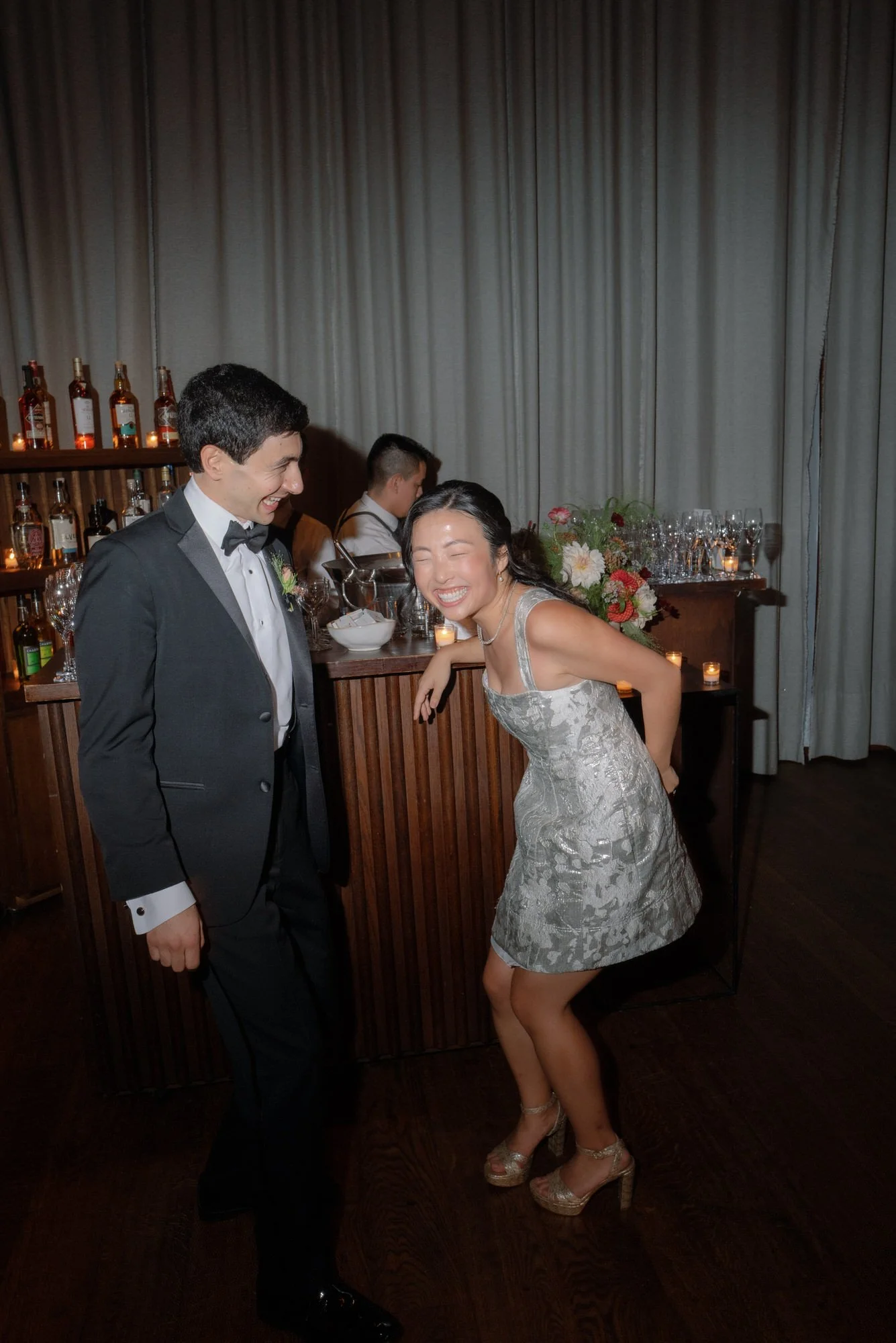 Bride and groom sharing a laugh by the bar during the reception at Blue Hill at Stone Barns, photographed by Jenny Fu.