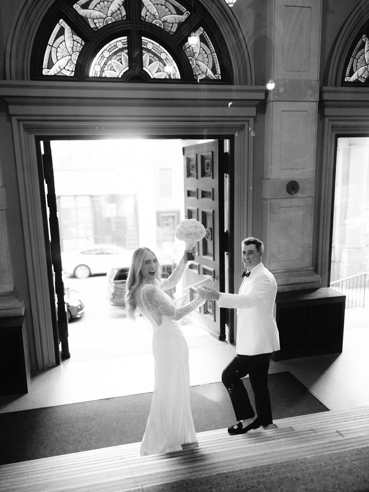 Bride and groom holding hands and smiling as they descend the steps inside St. Francis Xavier Church in Chelsea, photographed by Jenny Fu.