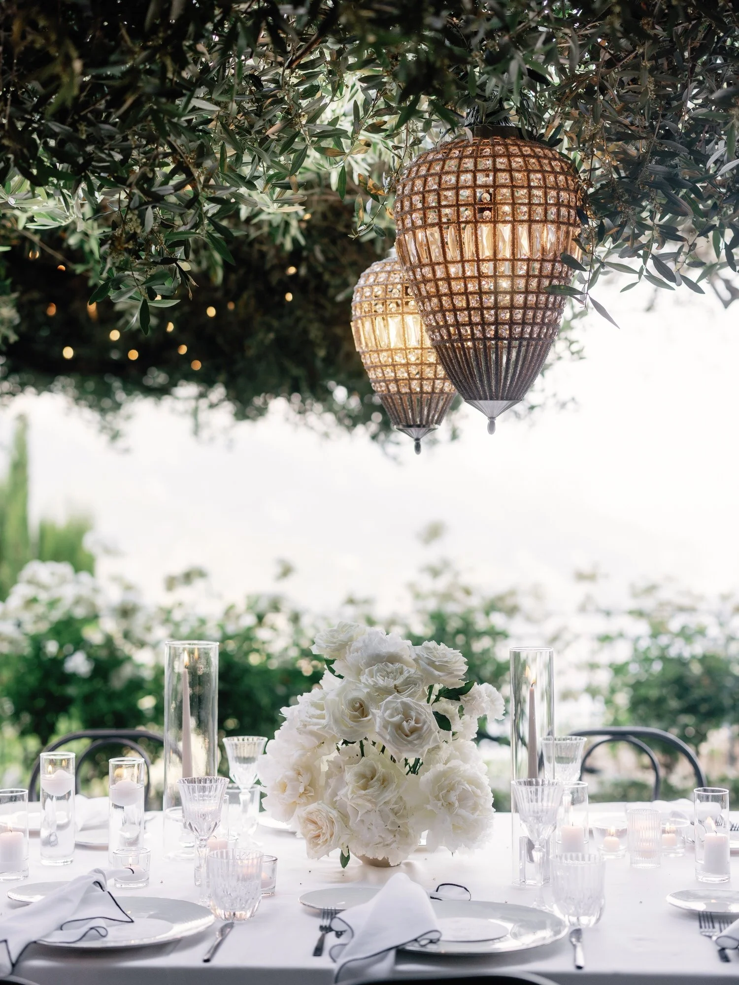 Crystal lanterns glowing above a candlelit dinner table adorned with white flowers at Caruso, A Belmond Hotel in Ravello, Italy, photographed by Jenny Fu.