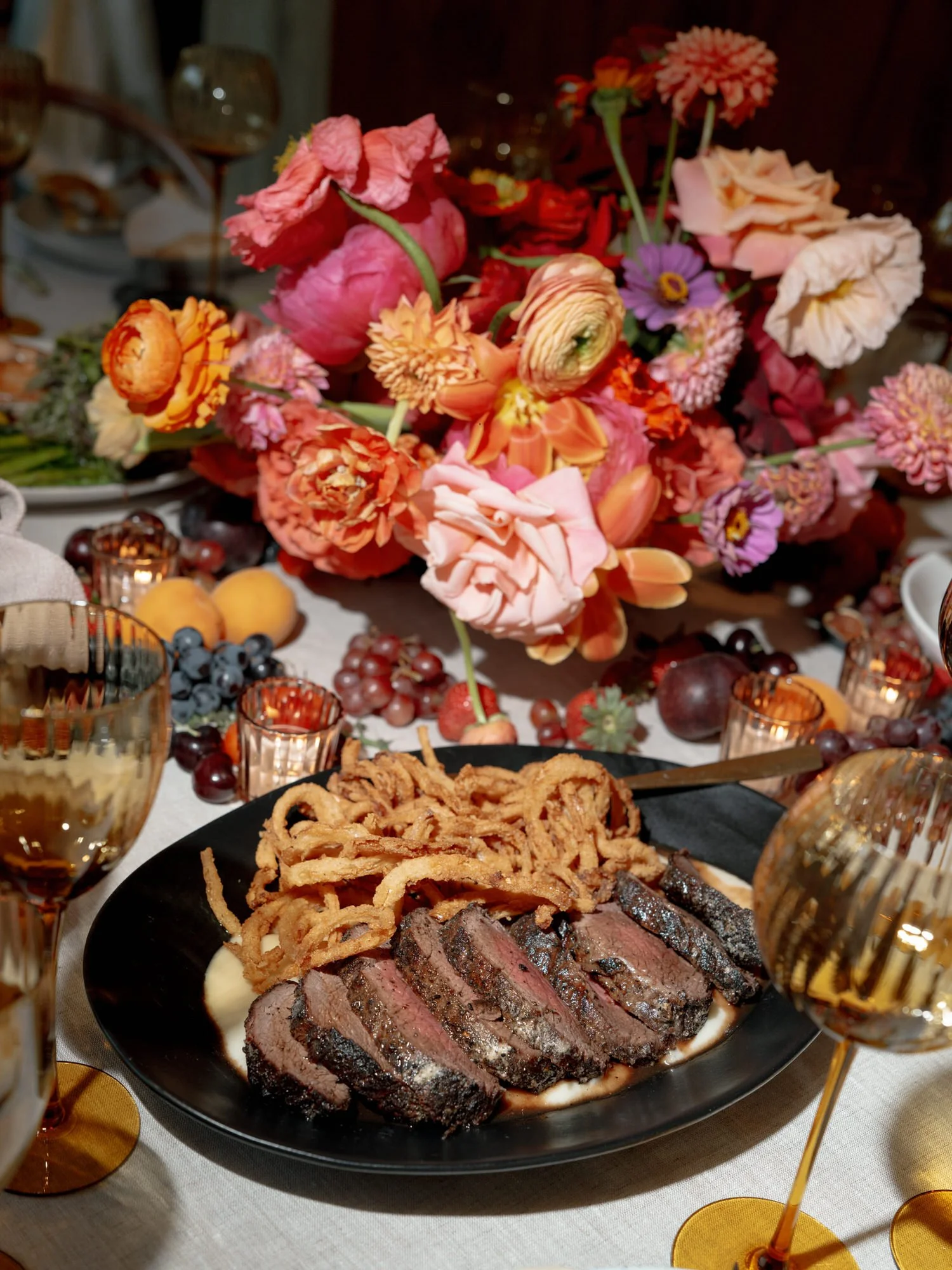 Plated sliced filet of beef with crispy onions beside vibrant summer florals on the dinner table at Valley Rock Inn in Sloatsburg, photographed by Jenny Fu.