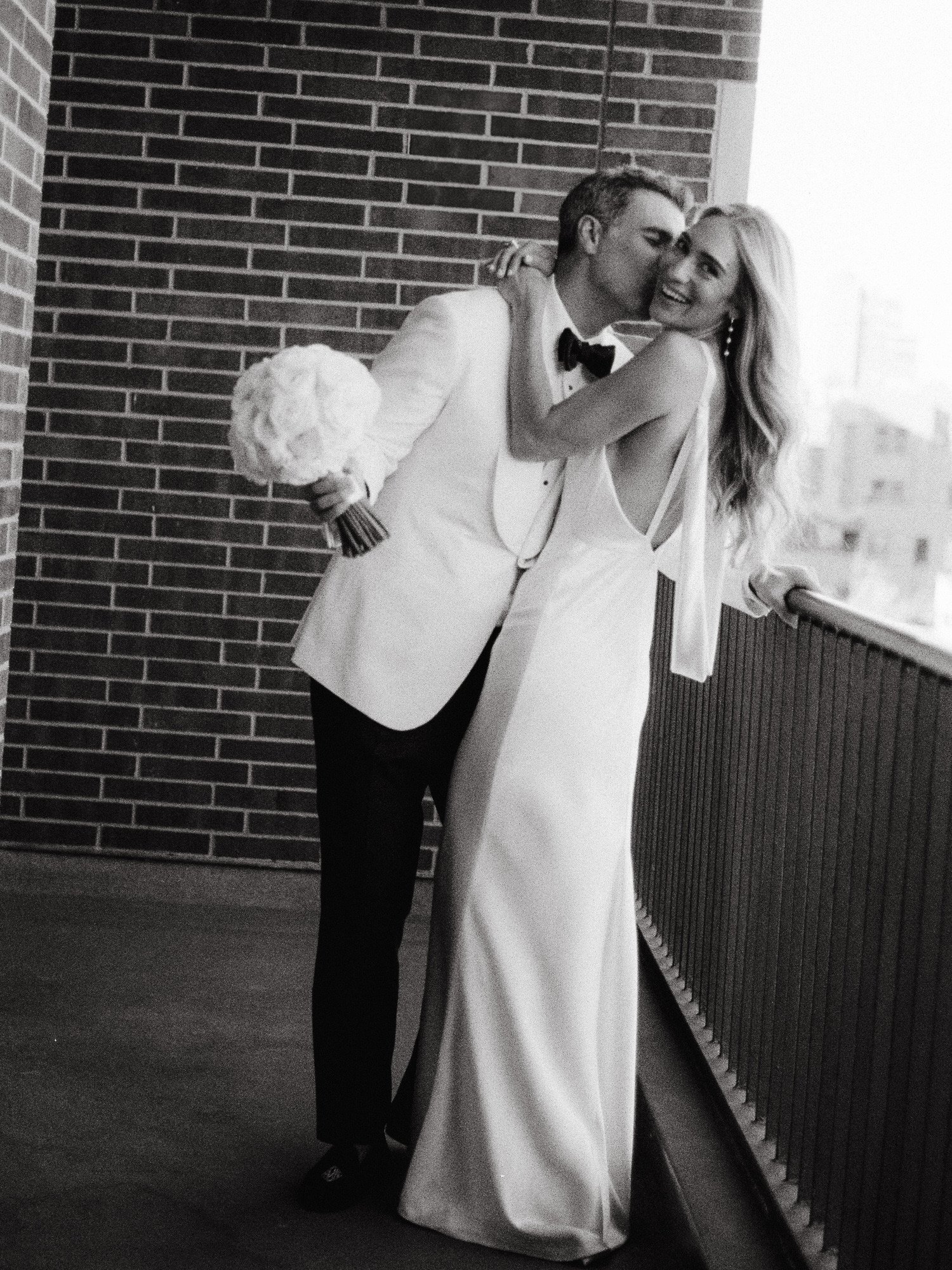 Groom kissing bride’s cheek on the private balcony of Crosby Street Hotel in Soho, photographed by Jenny Fu.
