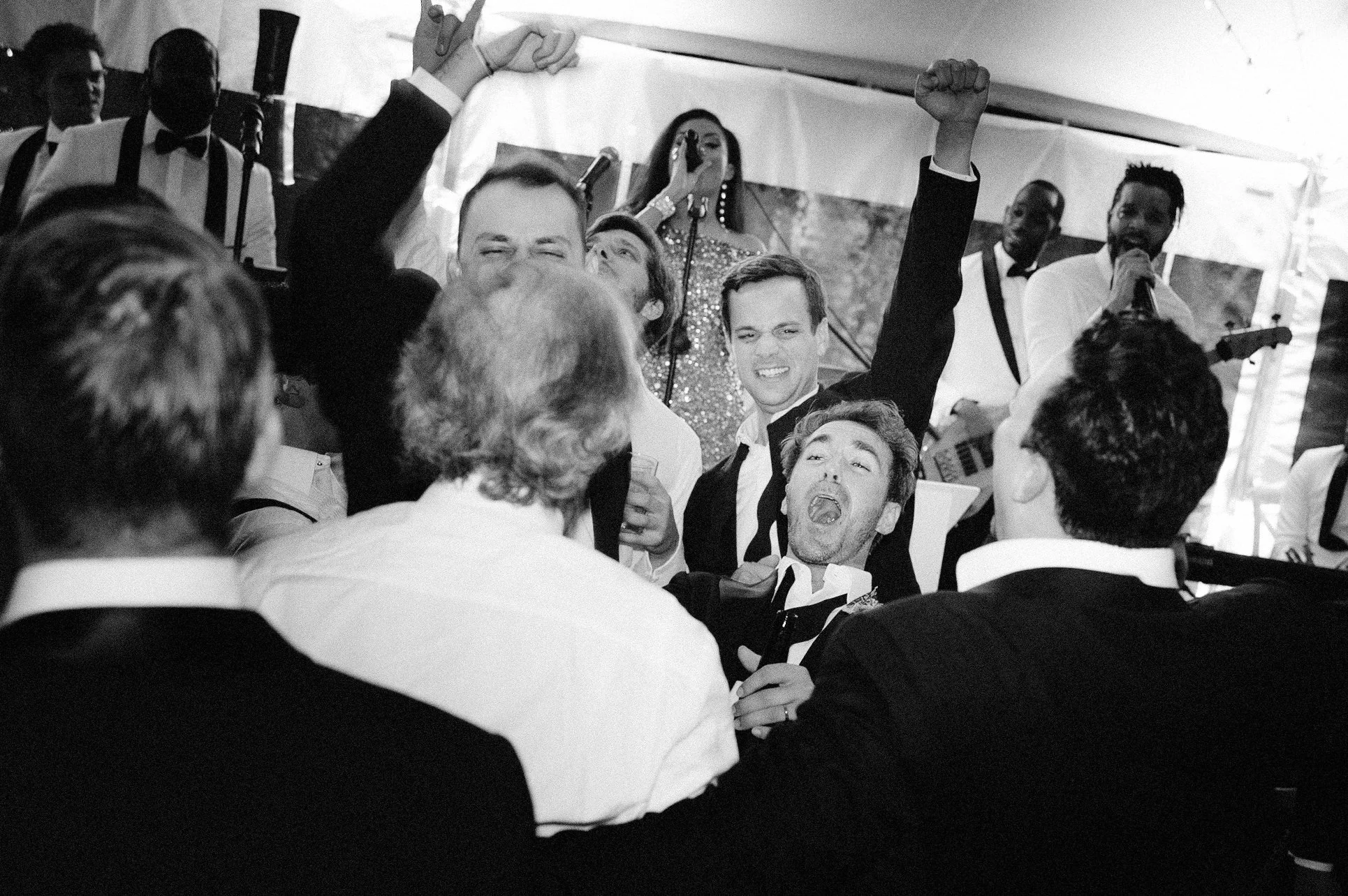 Groom lifted in the air by friends while celebrating on the dance floor
