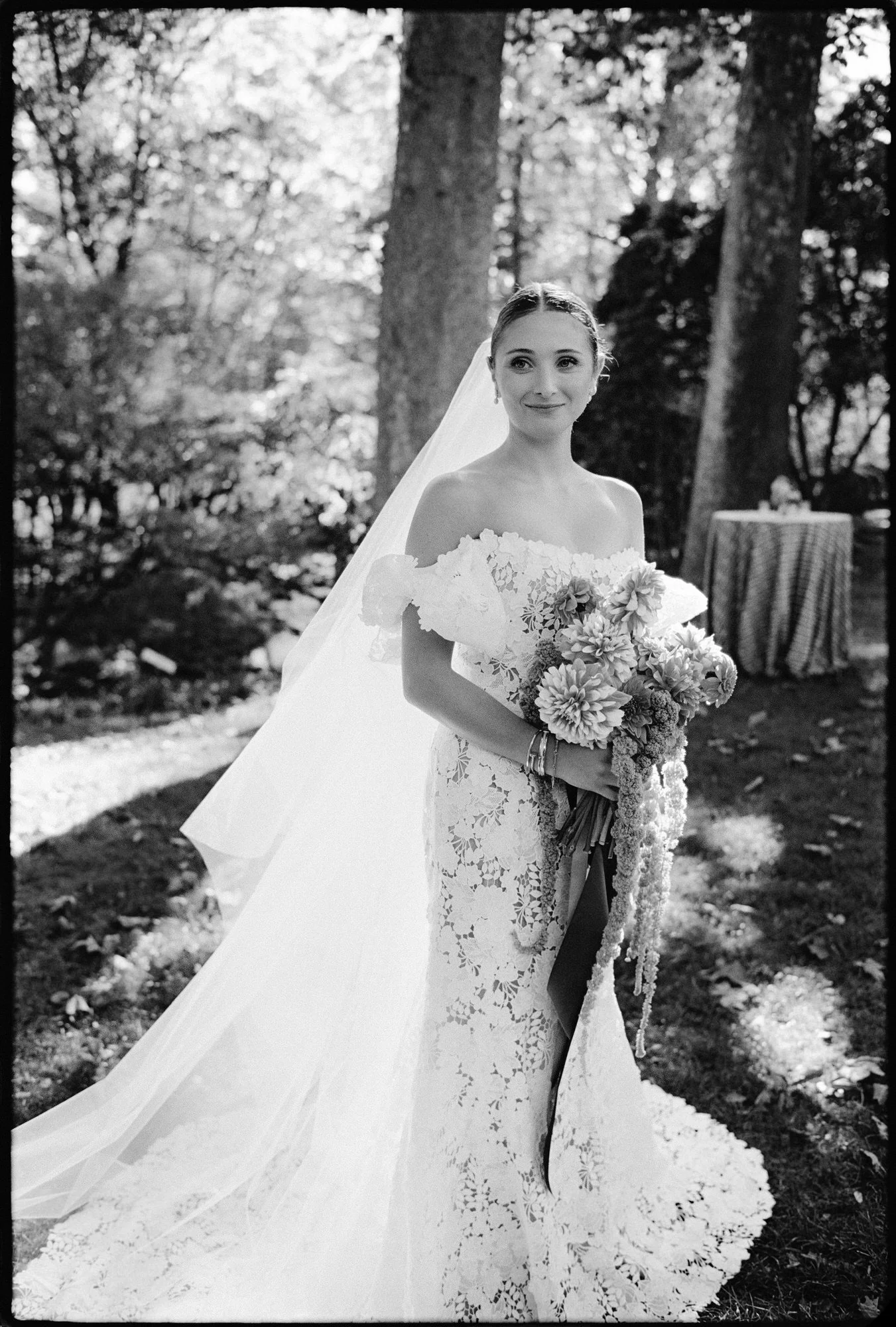 Bride holding her cascading bouquet beneath the trees before the ceremony at Troutbeck in Amenia, photographed by Jenny Fu.