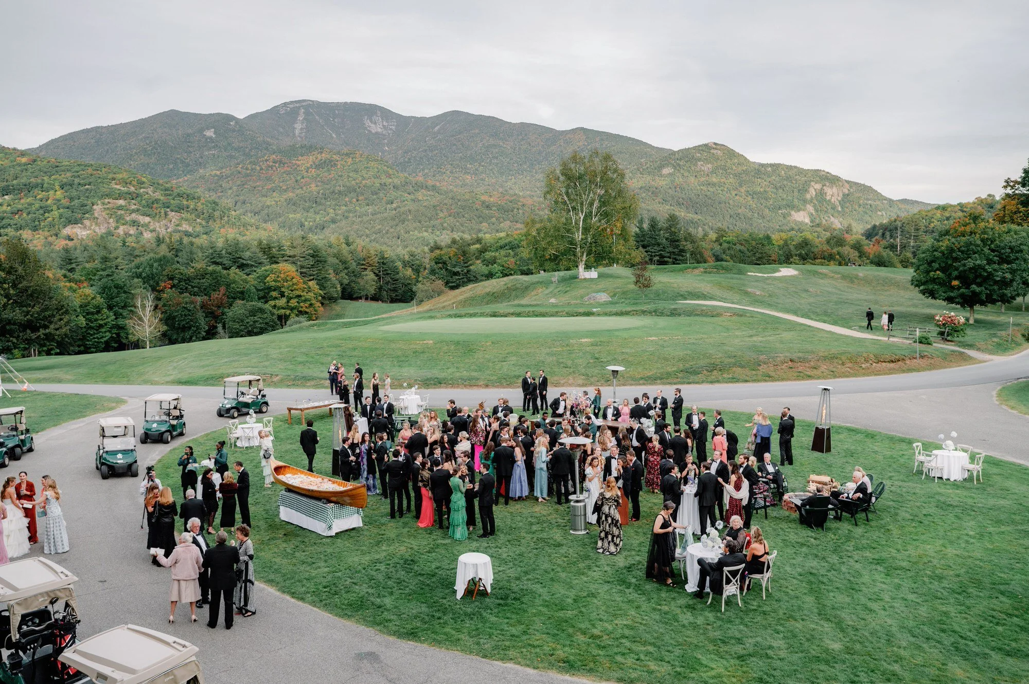 Aerial view of wedding guests mingling during cocktail hour on the lawn at The Ausable Club in the Adirondacks