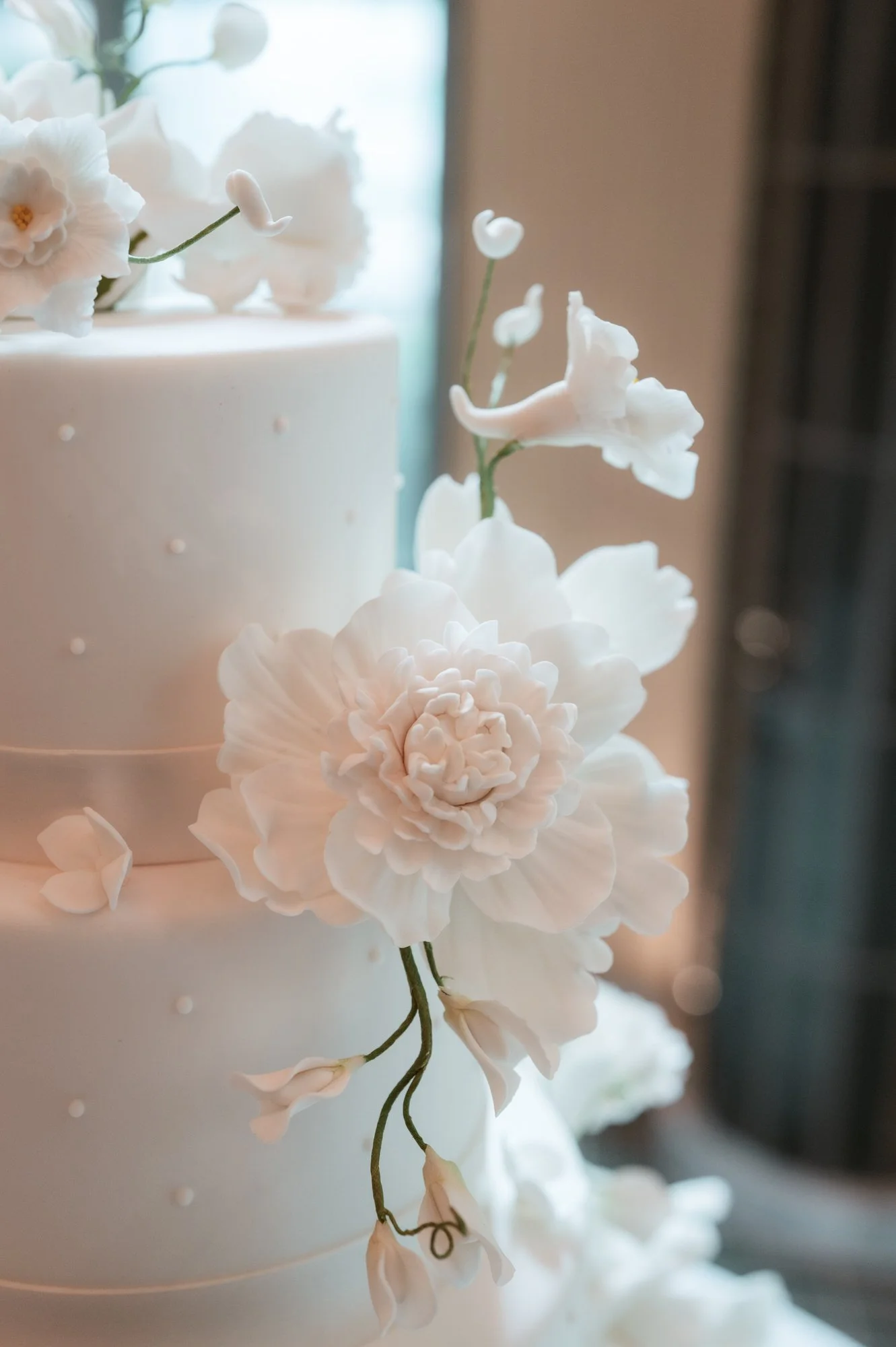 Close-up of white sugar flowers on a tiered wedding cake at the Waldorf Astoria New York, photographed by Jenny Fu.