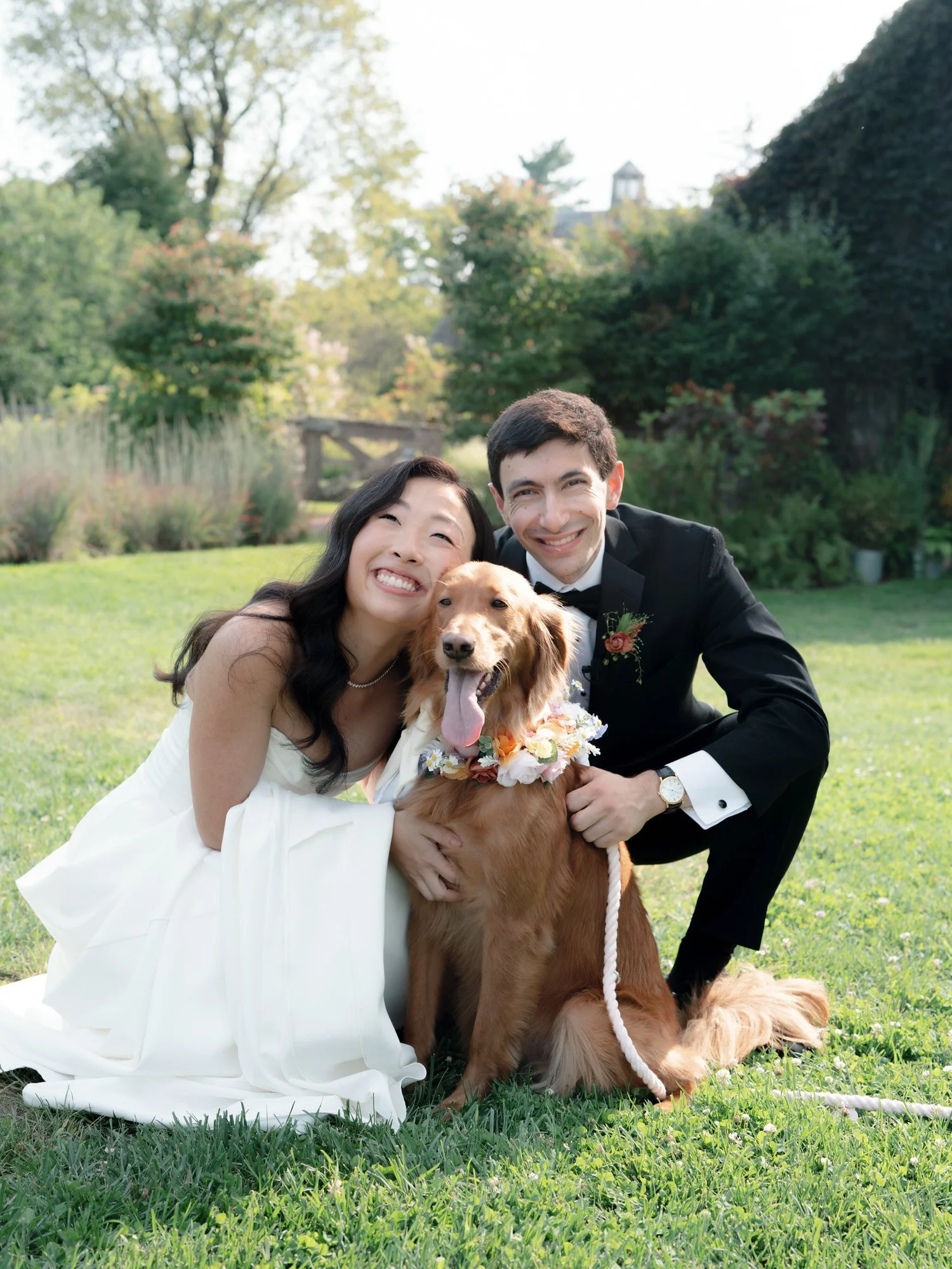 Bride and groom kneeling on the lawn with their dog wearing a floral collar at Blue Hill at Stone Barns, photographed by Jenny Fu.
