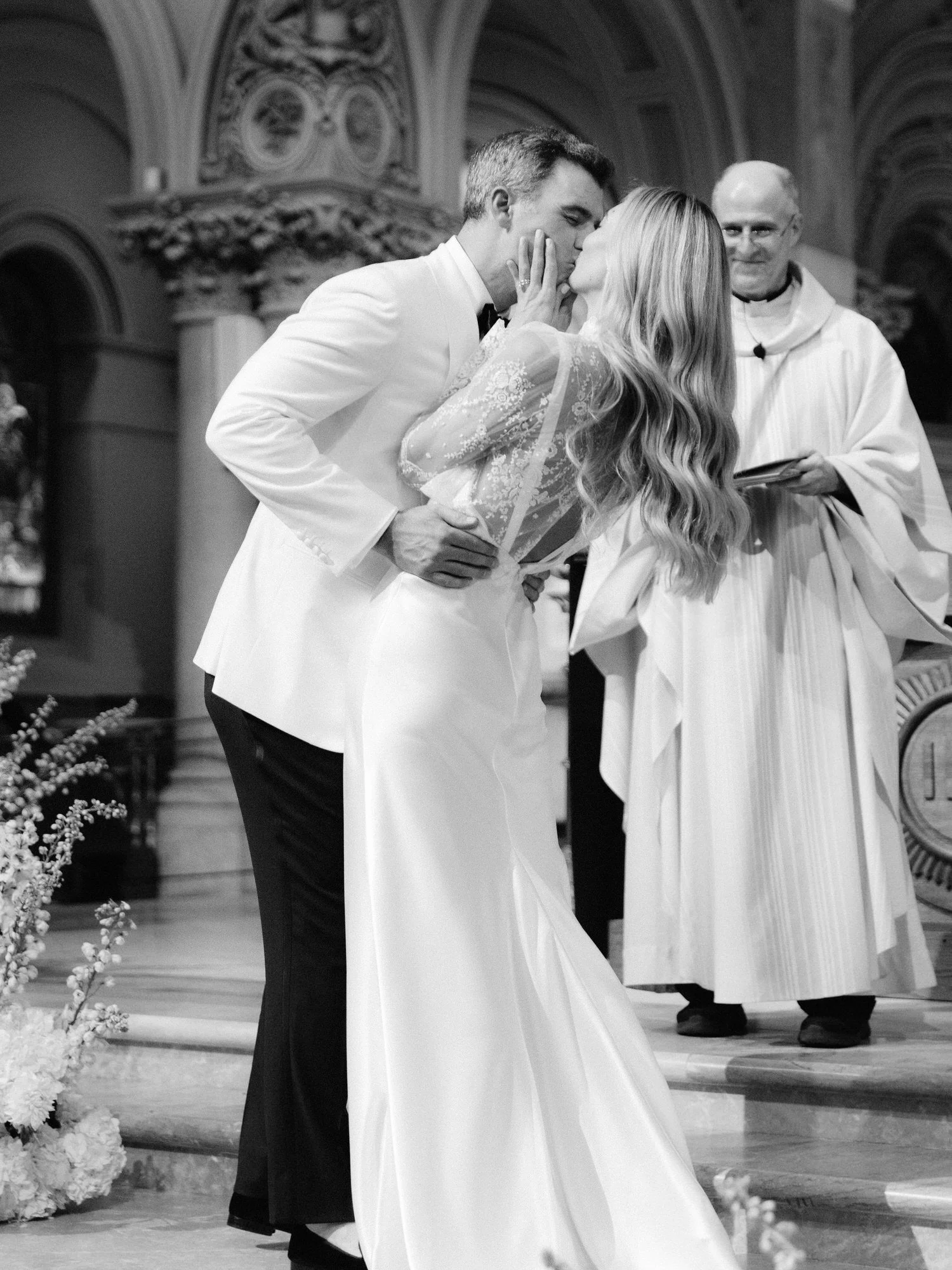Bride and groom sharing their first kiss at the altar surrounded by candlelight at St. Francis Xavier Church in Chelsea, photographed by Jenny Fu.