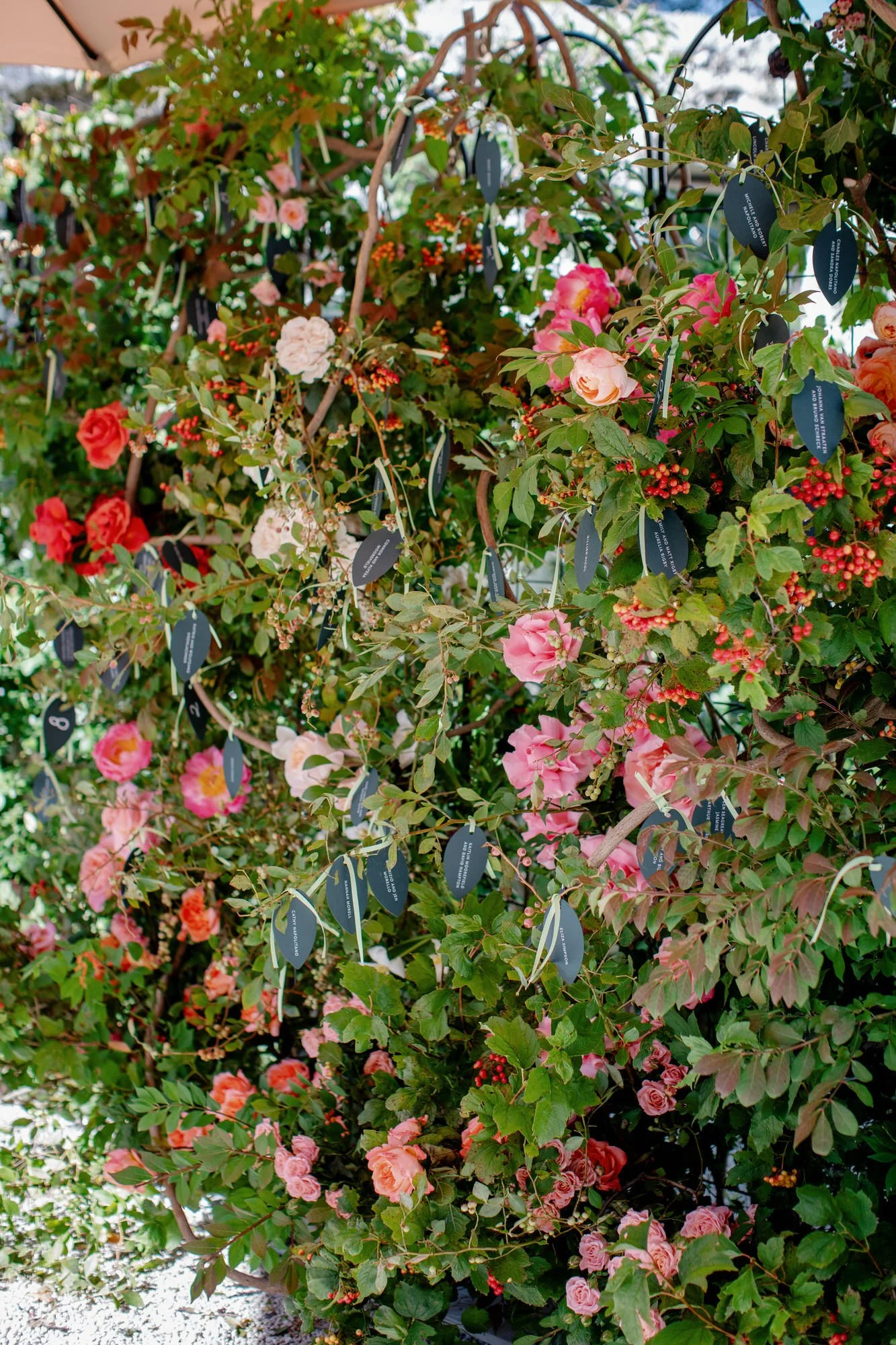 Seating chart tags woven into a wall of roses and greenery at Valley Rock Inn in Sloatsburg, photographed by Jenny Fu.