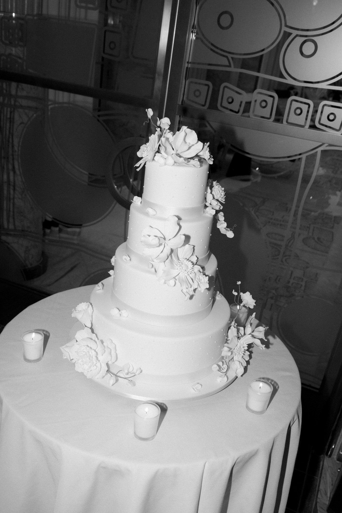 Black and white photo of a four-tier wedding cake by Ron Ben Israel with sugar flowers at a Waldorf Astoria New York wedding, photographed by Jenny Fu.