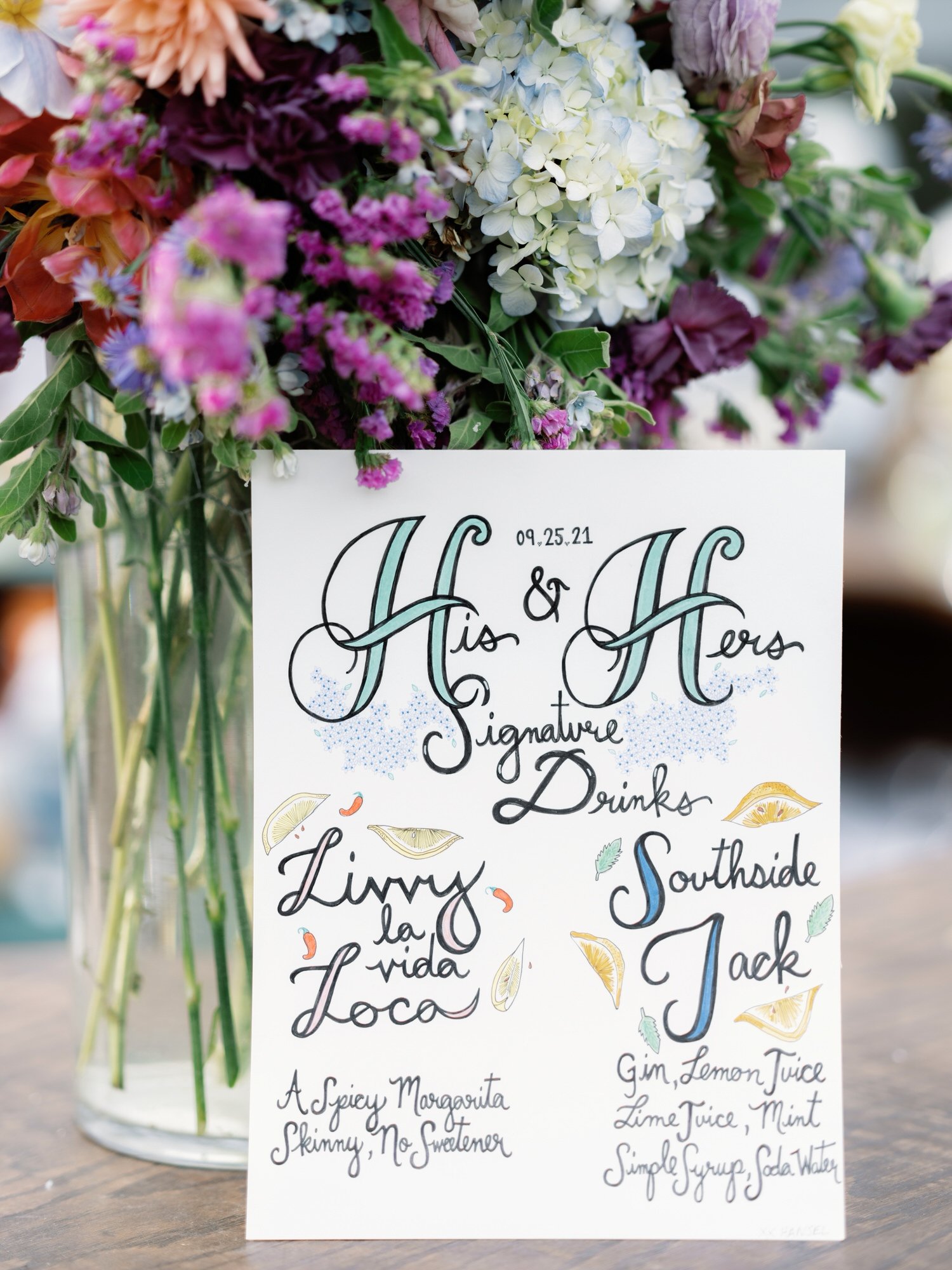Hand-painted sign featuring his and hers signature cocktails surrounded by florals at The Ausable Club in the Adirondacks