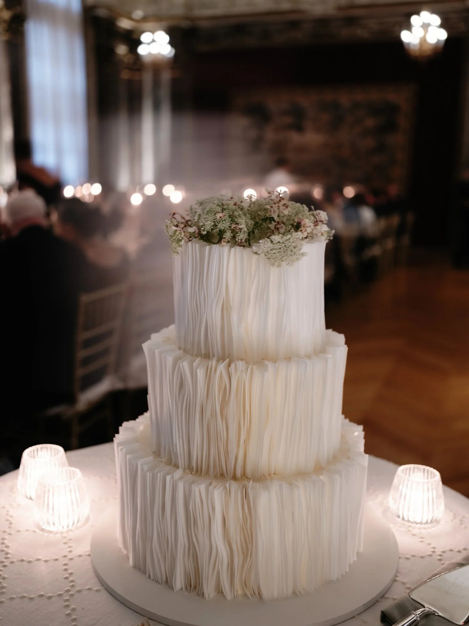 Three-tiered modern white wedding cake with floral topper at Burden Kahn Mansion