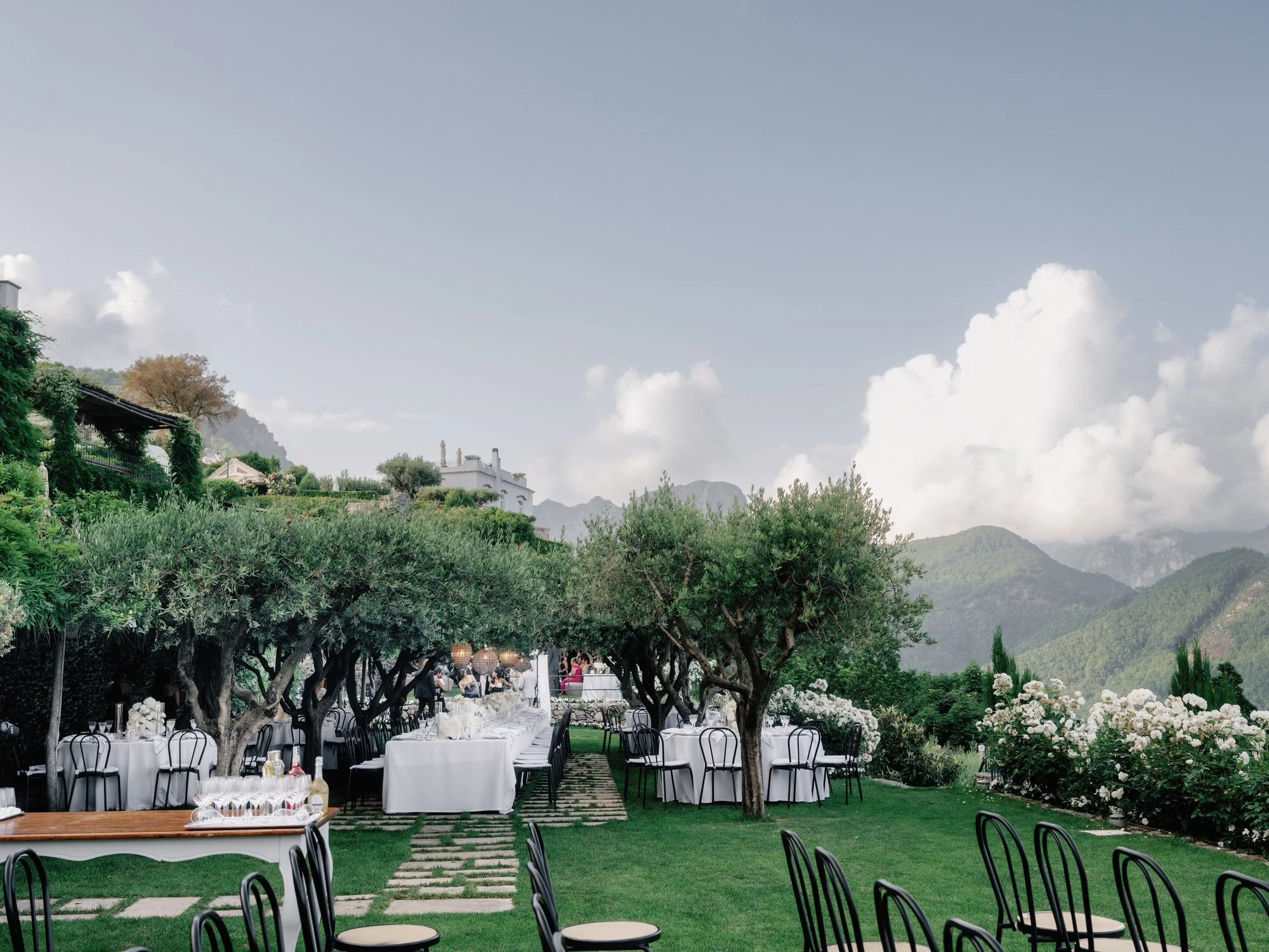 Refined dinner place setting with white peonies and candles on a linen table at Caruso, A Belmond Hotel in Ravello, Italy, photographed by Jenny Fu.