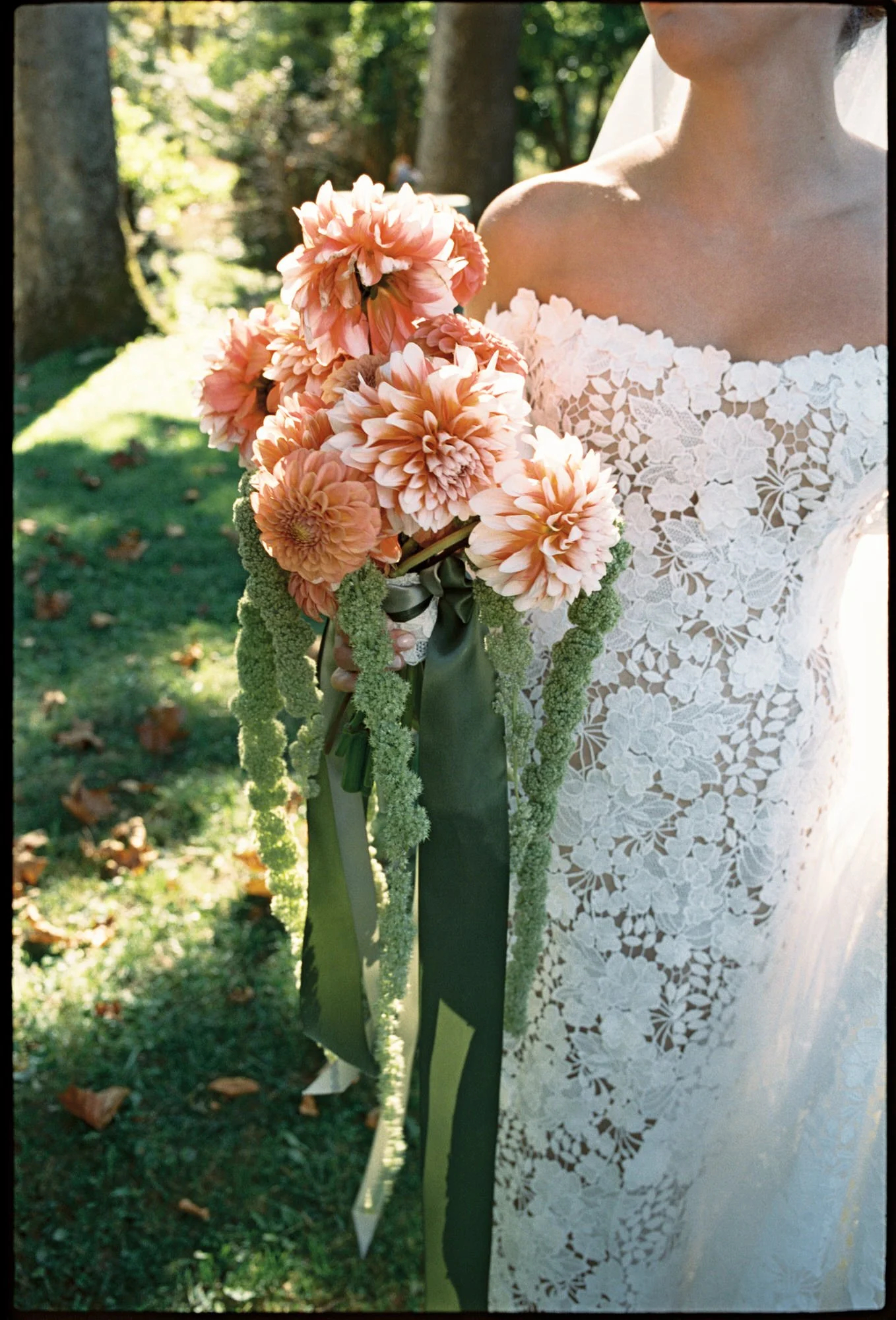 Close-up of bride’s hand holding a lush peach dahlia bouquet with green trailing amaranthus at Troutbeck in Amenia, photographed by Jenny Fu.