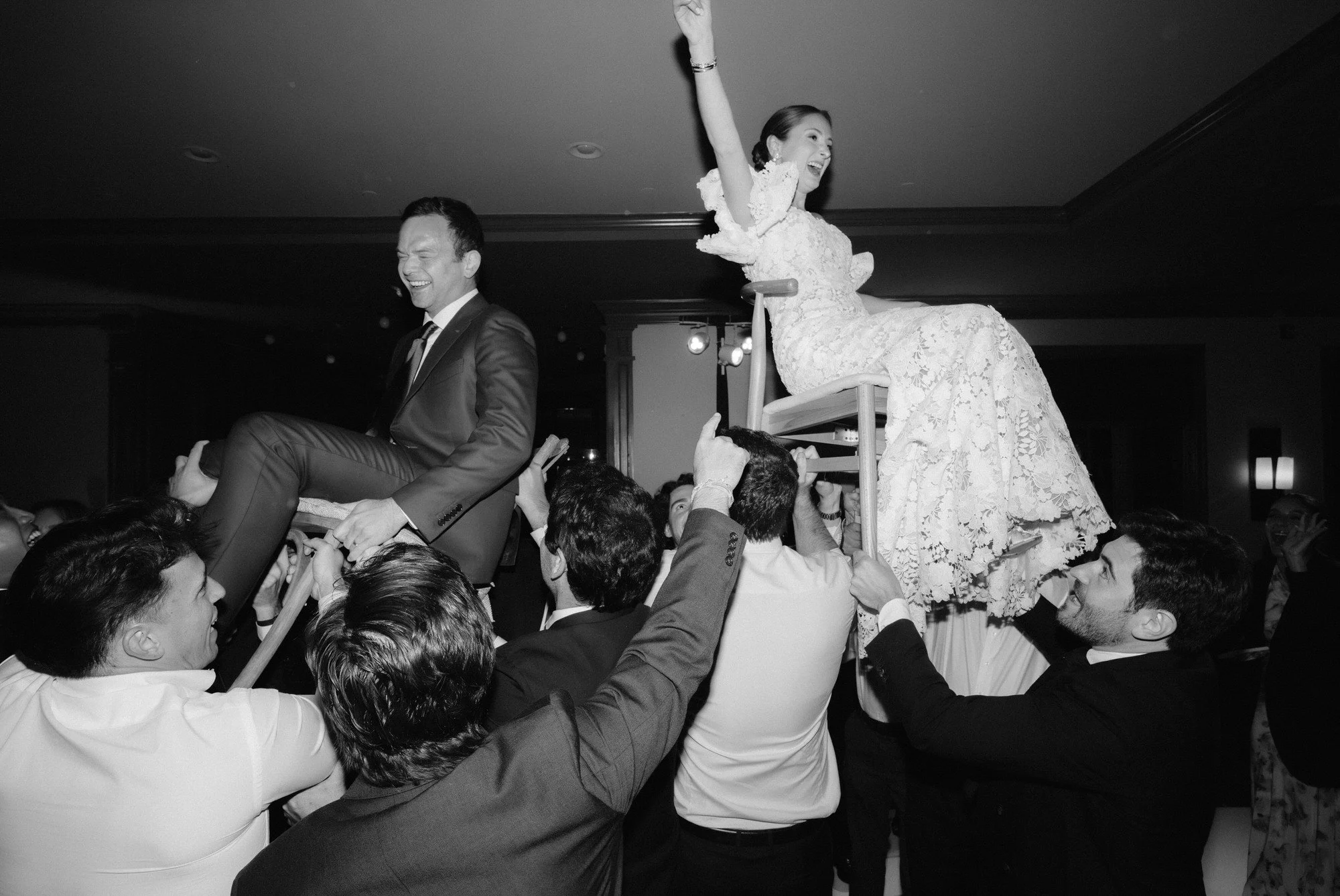 Bride and groom lifted in chairs during the hora surrounded by cheering guests at Troutbeck in Amenia, photographed by Jenny Fu.