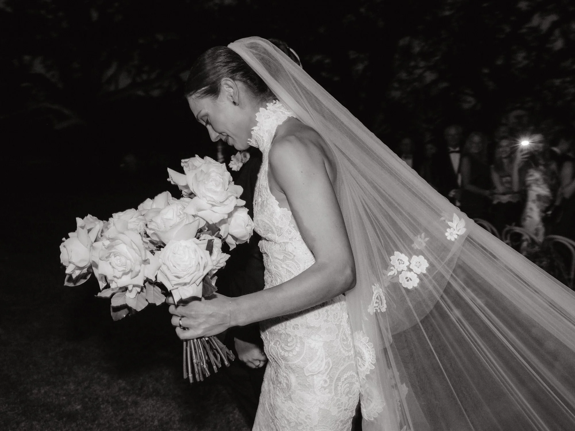 Bride walking down the aisle holding white roses with lace veil flowing behind her at The Dunlin, Auberge, photographed by Jenny Fu.