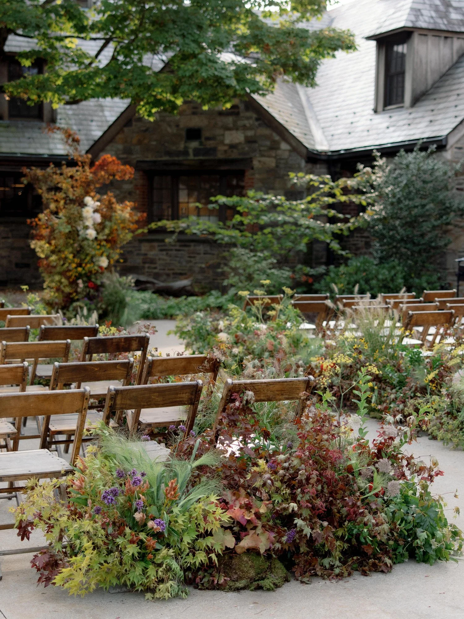 Ceremony seating with meadow-style aisle flowers surrounding wooden chairs in the courtyard at Blue Hill at Stone Barns, photographed by Jenny Fu.