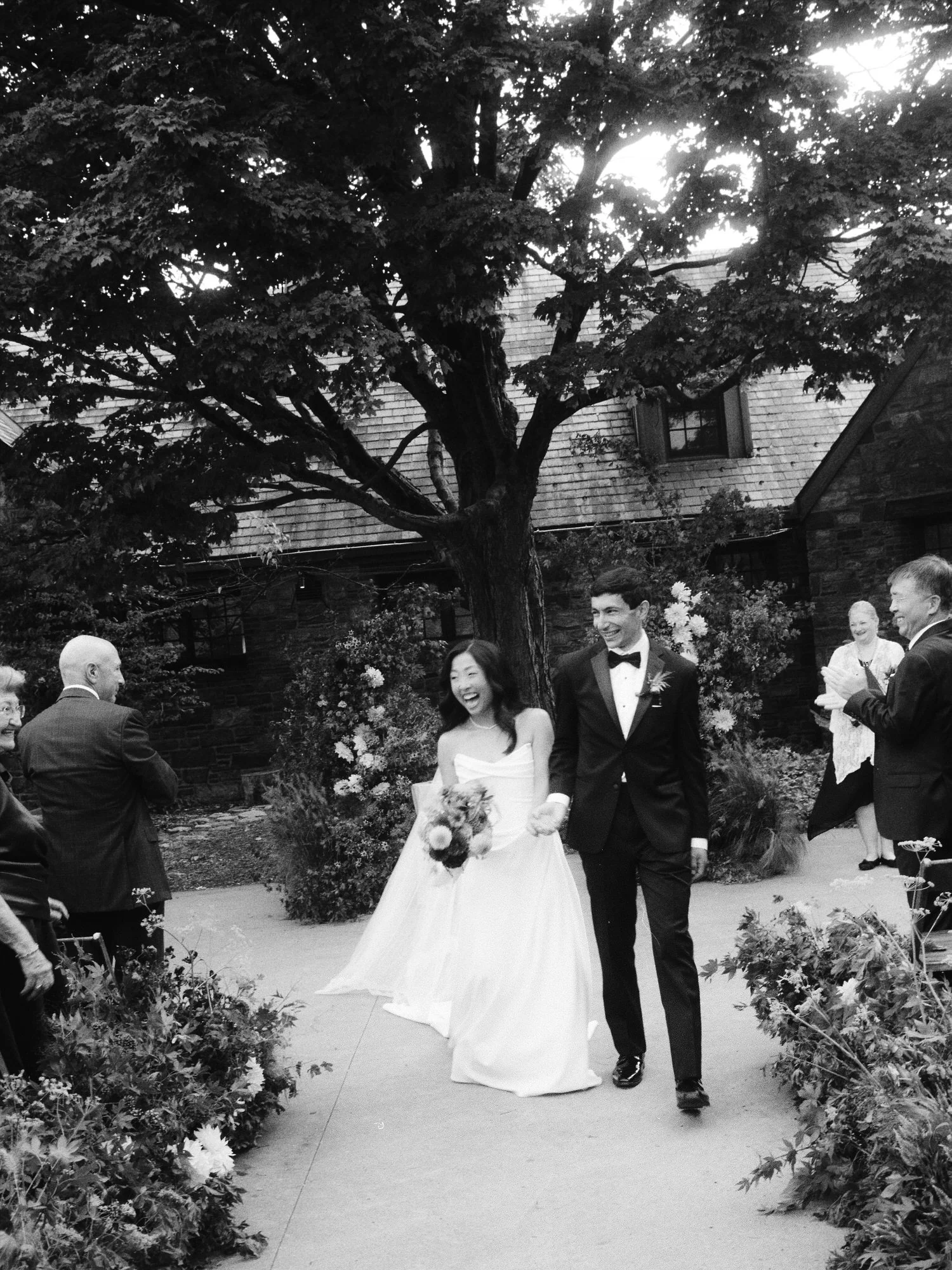 Just married, the couple walks back up the aisle smiling in black and white at Blue Hill at Stone Barns, photographed by Jenny Fu.