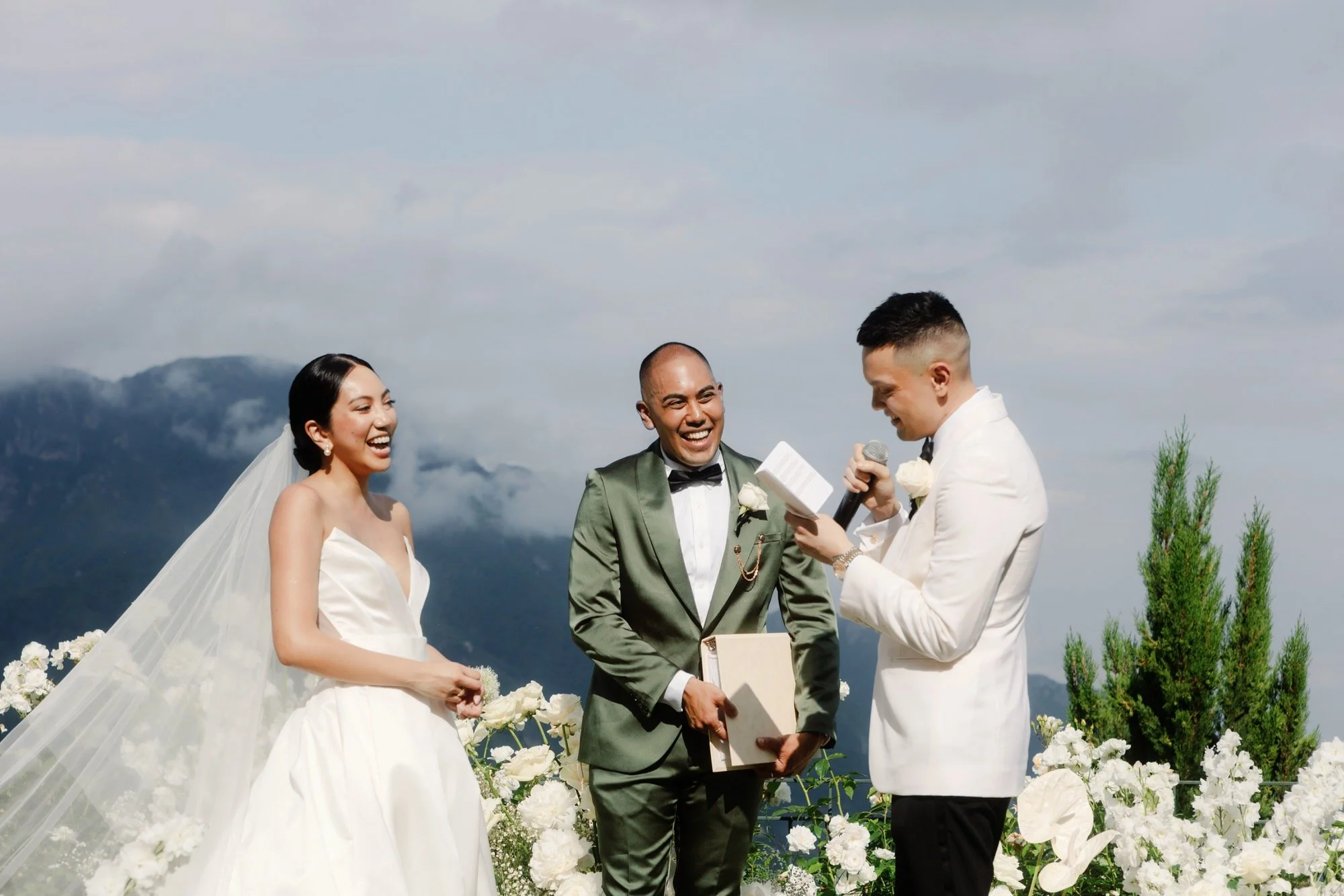 Groom reading his vows as the bride and officiant share a laugh during the ceremony overlooking the Amalfi Coast at Caruso, A Belmond Hotel in Ravello, Italy, photographed by Jenny Fu.