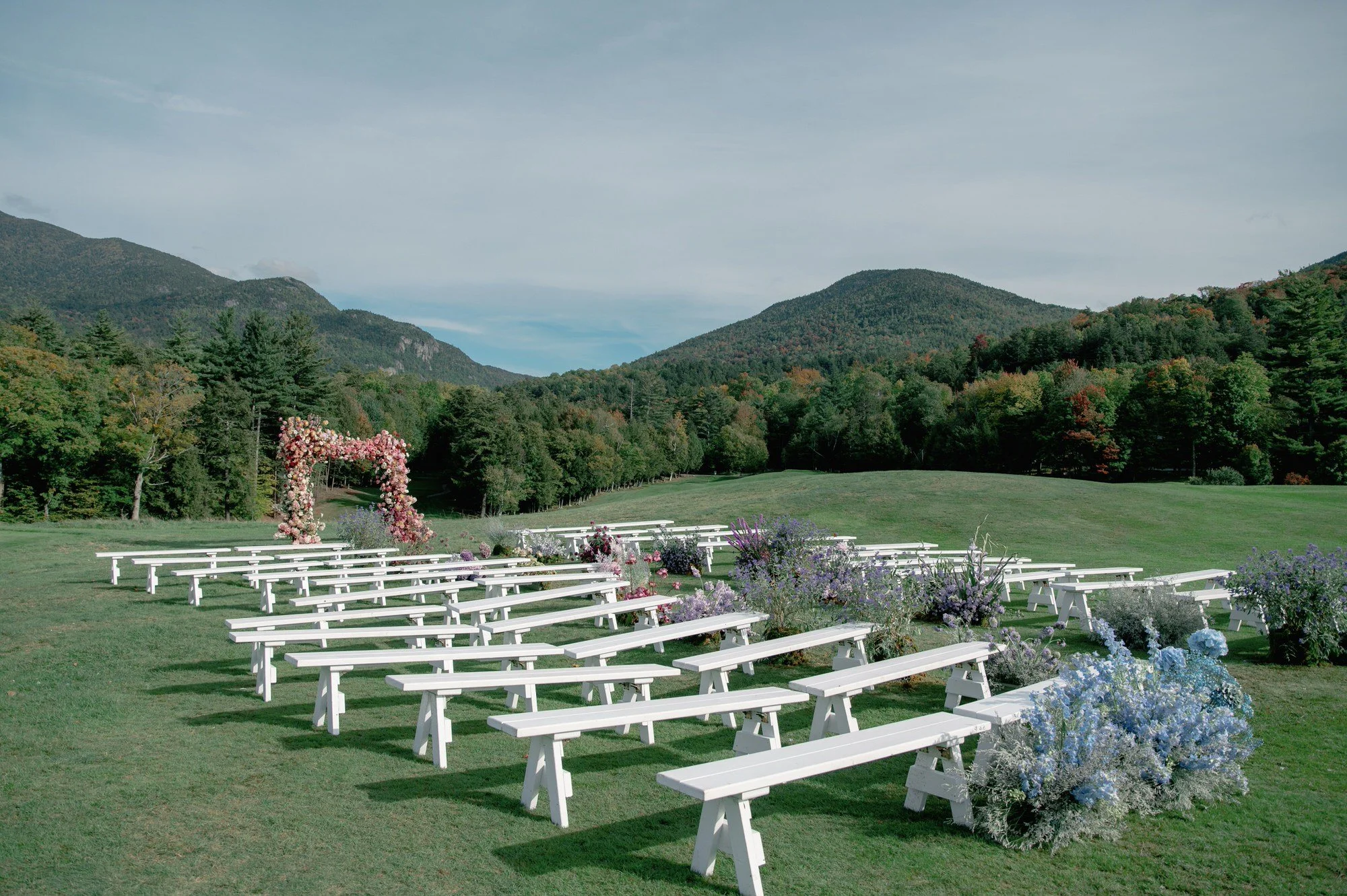 Outdoor wedding ceremony setup with floral arch and mountain views at Olivia and Jack’s wedding at the Ausable Club in the Adirondacks