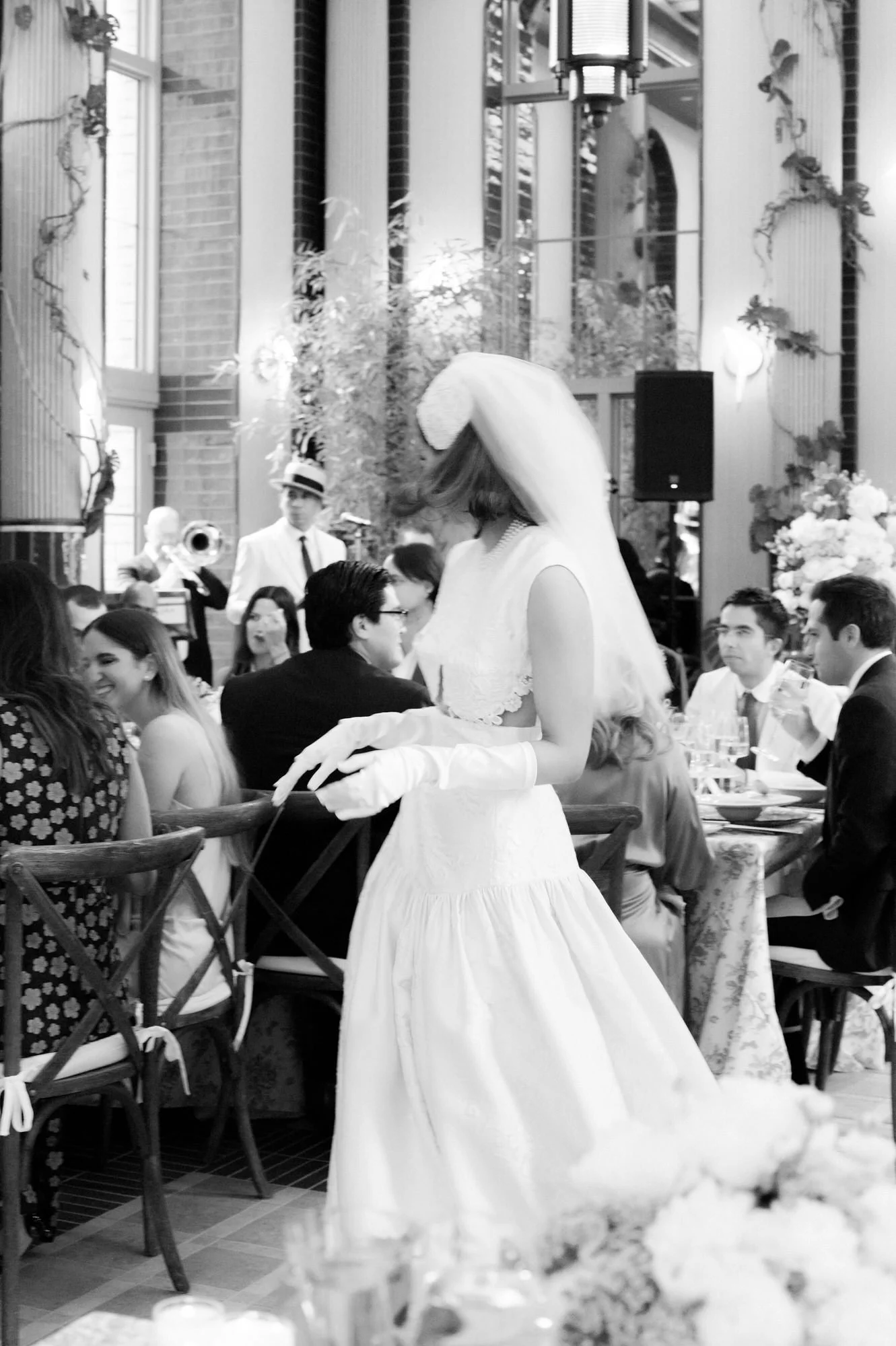 Black and white photo of the bride in her veil moving through reception tables as guests look on at the Waldorf Astoria New York, photographed by Jenny Fu.