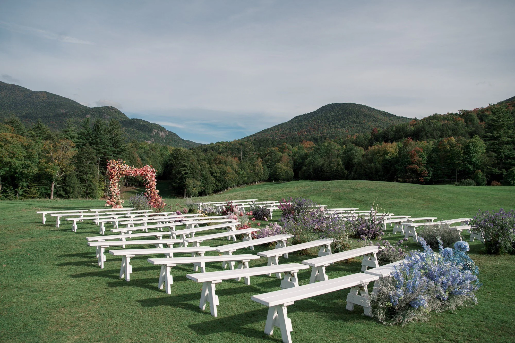 Outdoor wedding ceremony setup with floral arch and mountain backdrop at The Ausable Club in the Adirondack Mountains