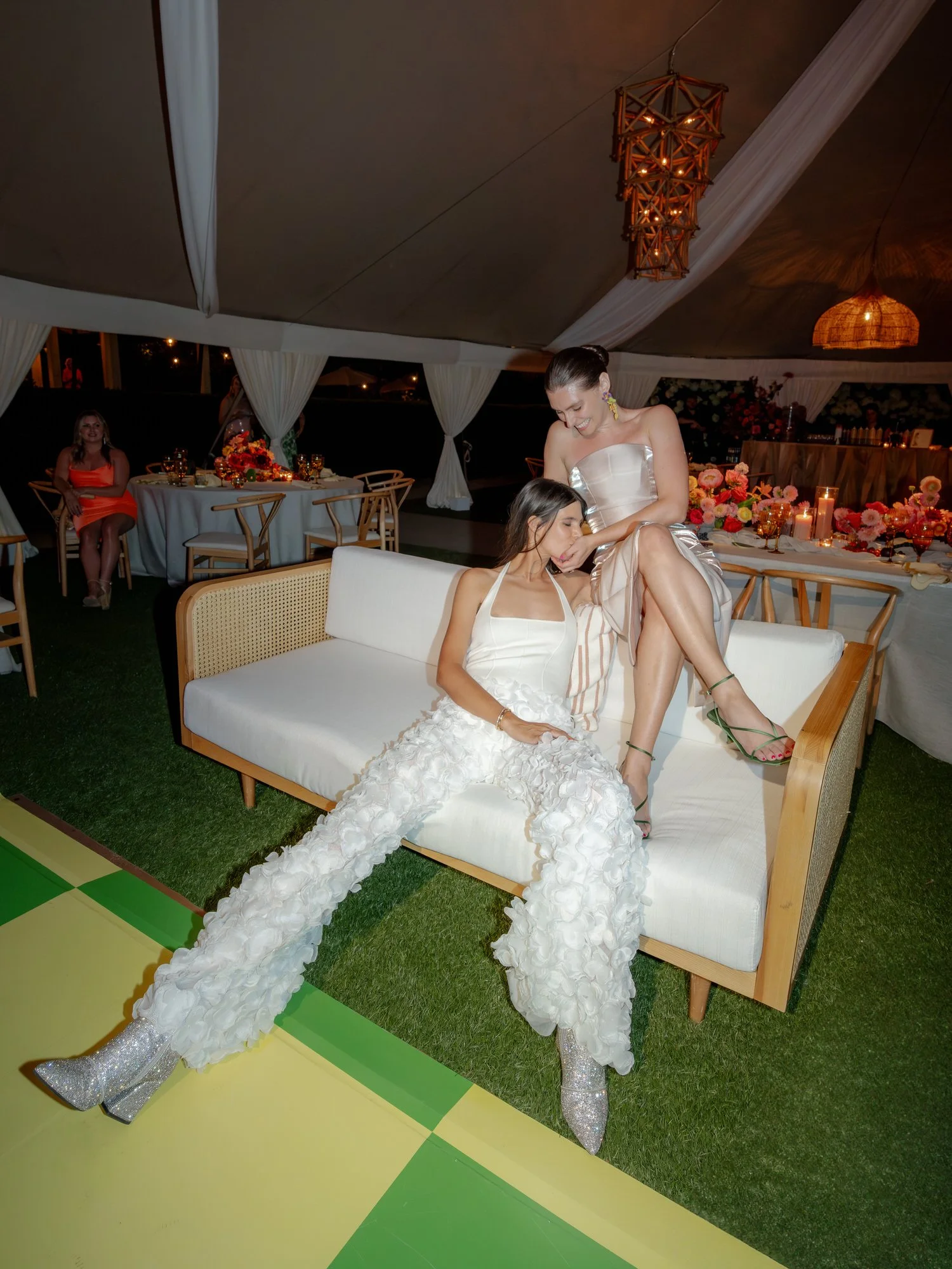 Two brides relaxing together on a white sofa after dancing beneath the tented reception lights at Valley Rock Inn in Sloatsburg, photographed by Jenny Fu.