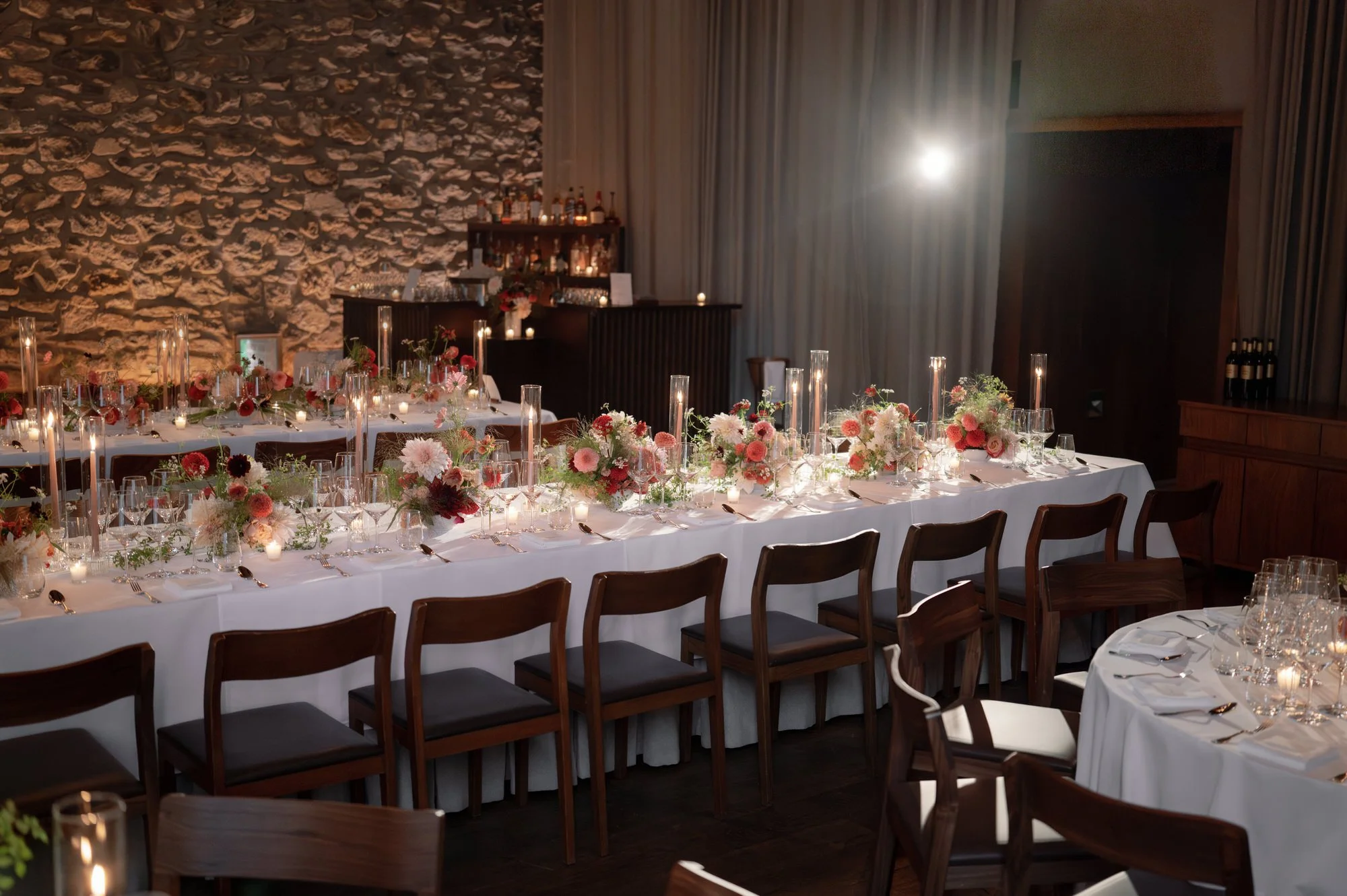 Reception room with long tables, candlelight, and garden-style floral centerpieces at Blue Hill at Stone Barns, photographed by Jenny Fu.