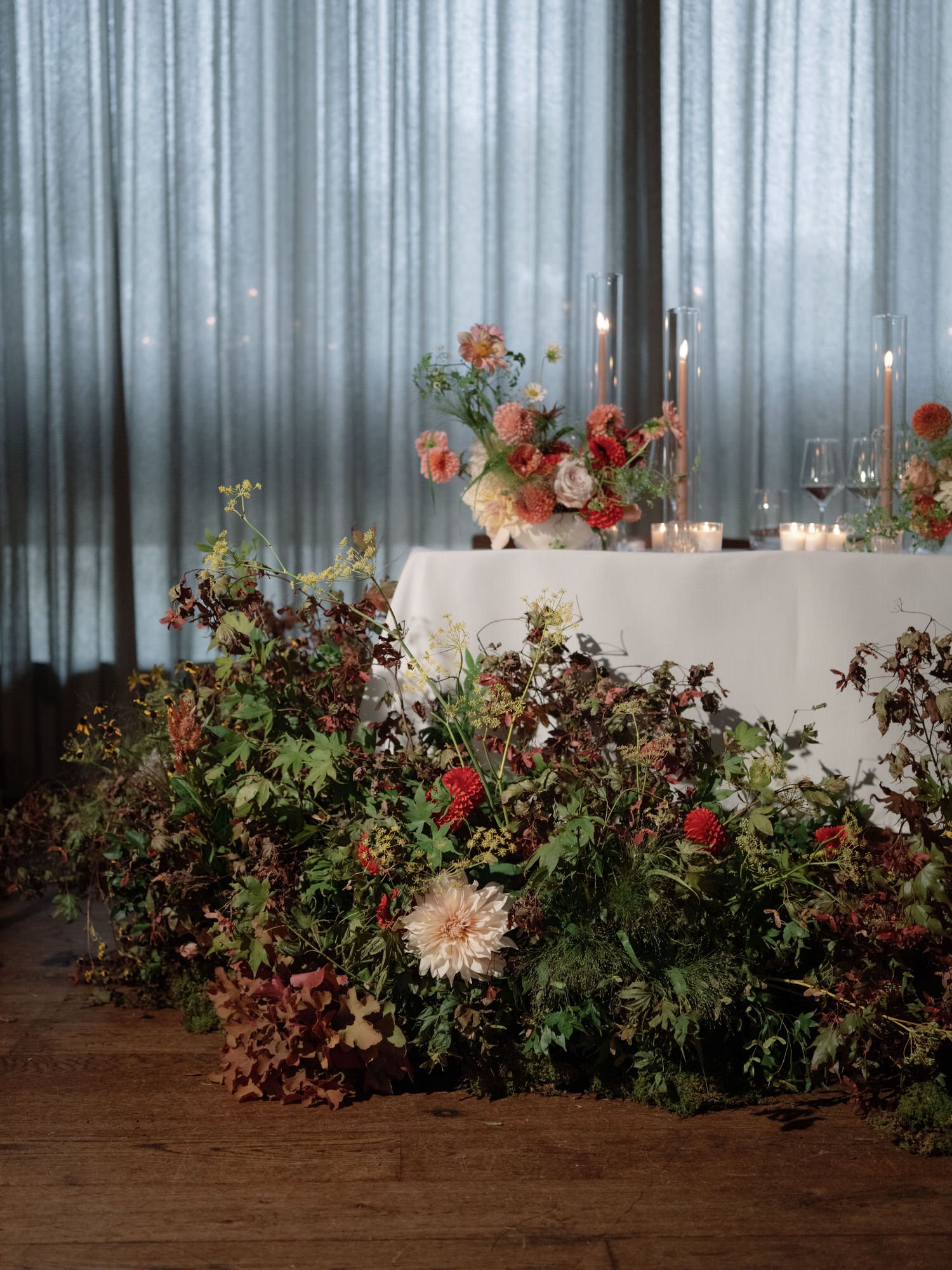 Meadow-style florals and candlelight surrounding the sweetheart table against soft drapery at Blue Hill at Stone Barns, photographed by Jenny Fu.