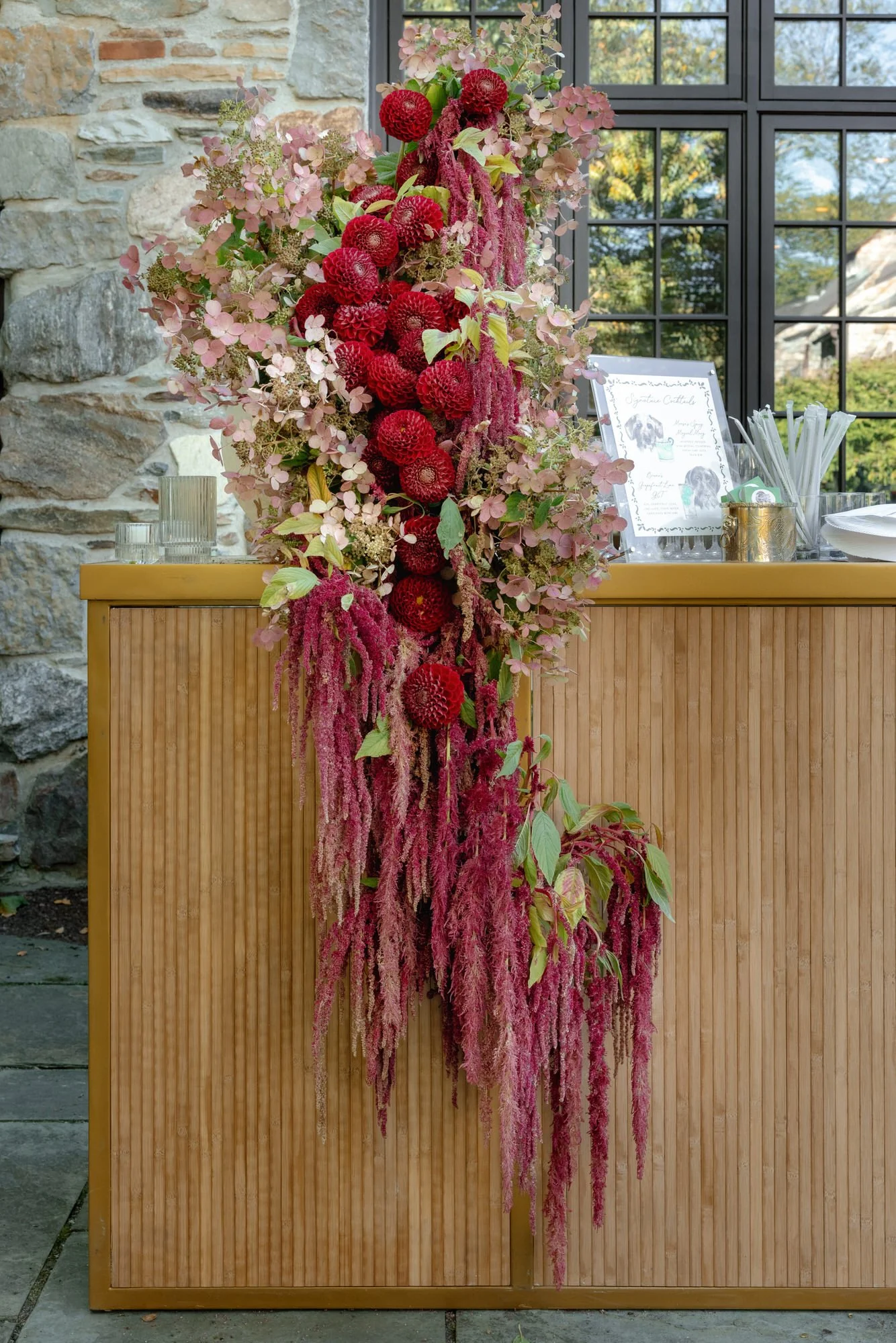 Bar floral installation featuring bold red dahlias and hanging burgundy amaranthus at Troutbeck in Amenia, photographed by Jenny Fu.
