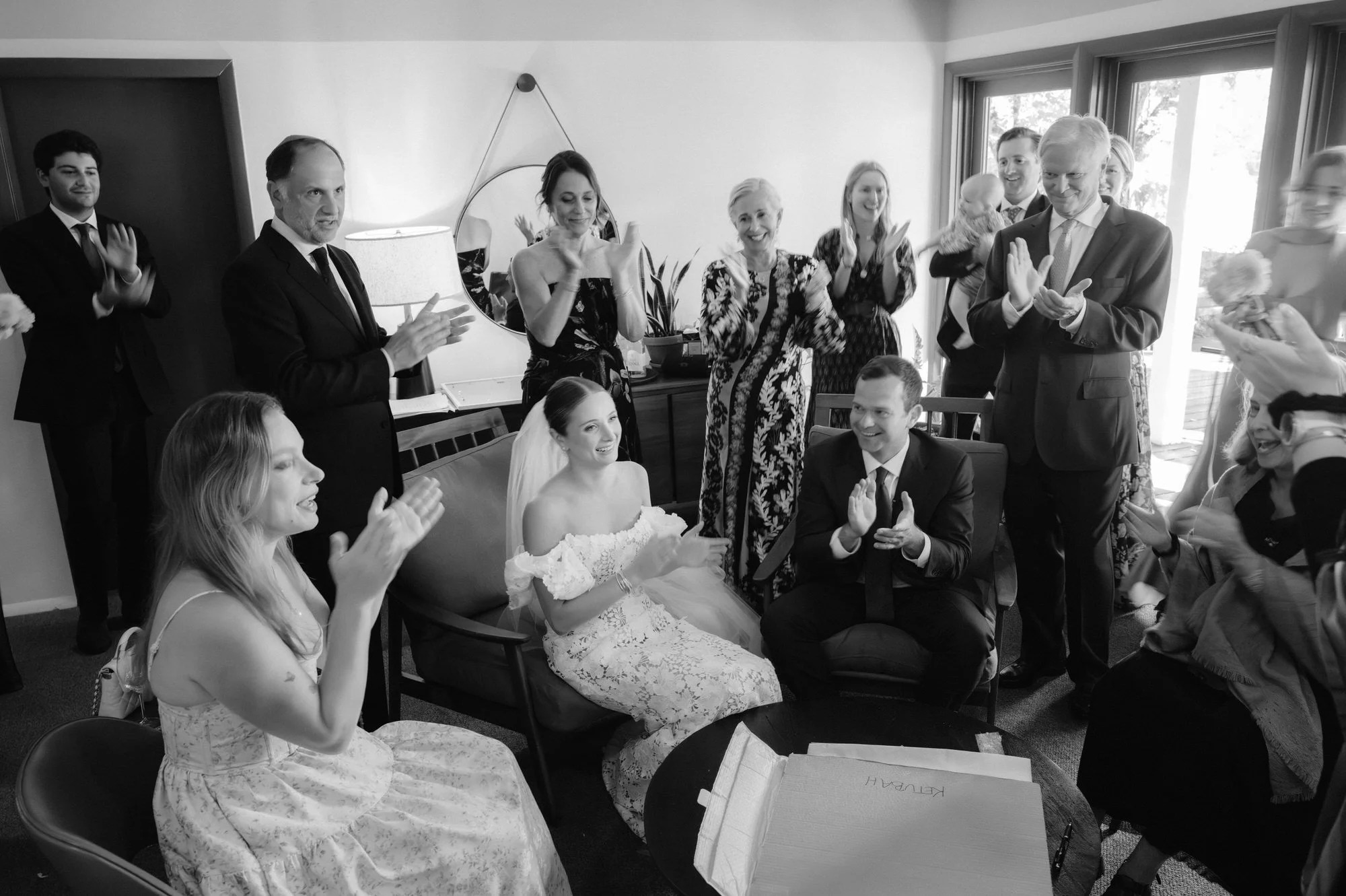 Family and friends clapping and celebrating with the bride and groom before the ceremony inside a suite at Troutbeck in Amenia, photographed by Jenny Fu.