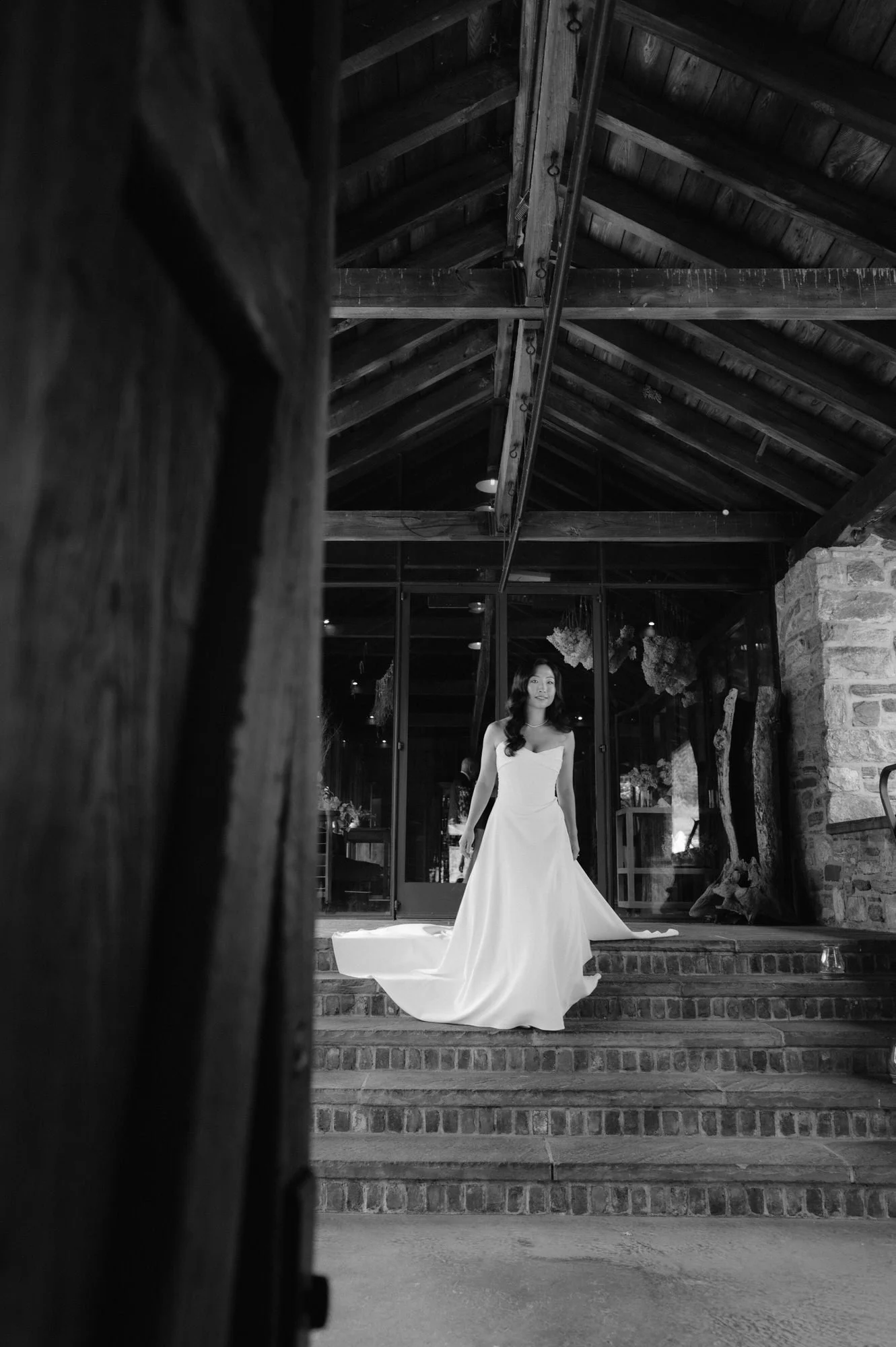 Bride descending the brick steps inside the barn in black and white at Blue Hill at Stone Barns, photographed by Jenny Fu.