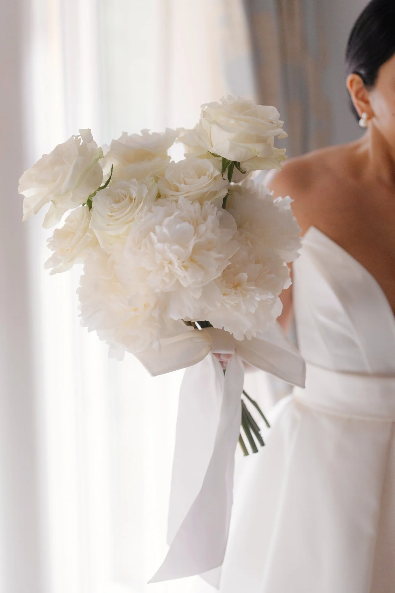 Close-up of the bride holding a white rose and peony bouquet tied with satin ribbon at Caruso, A Belmond Hotel in Ravello, Italy, photographed by Jenny Fu.