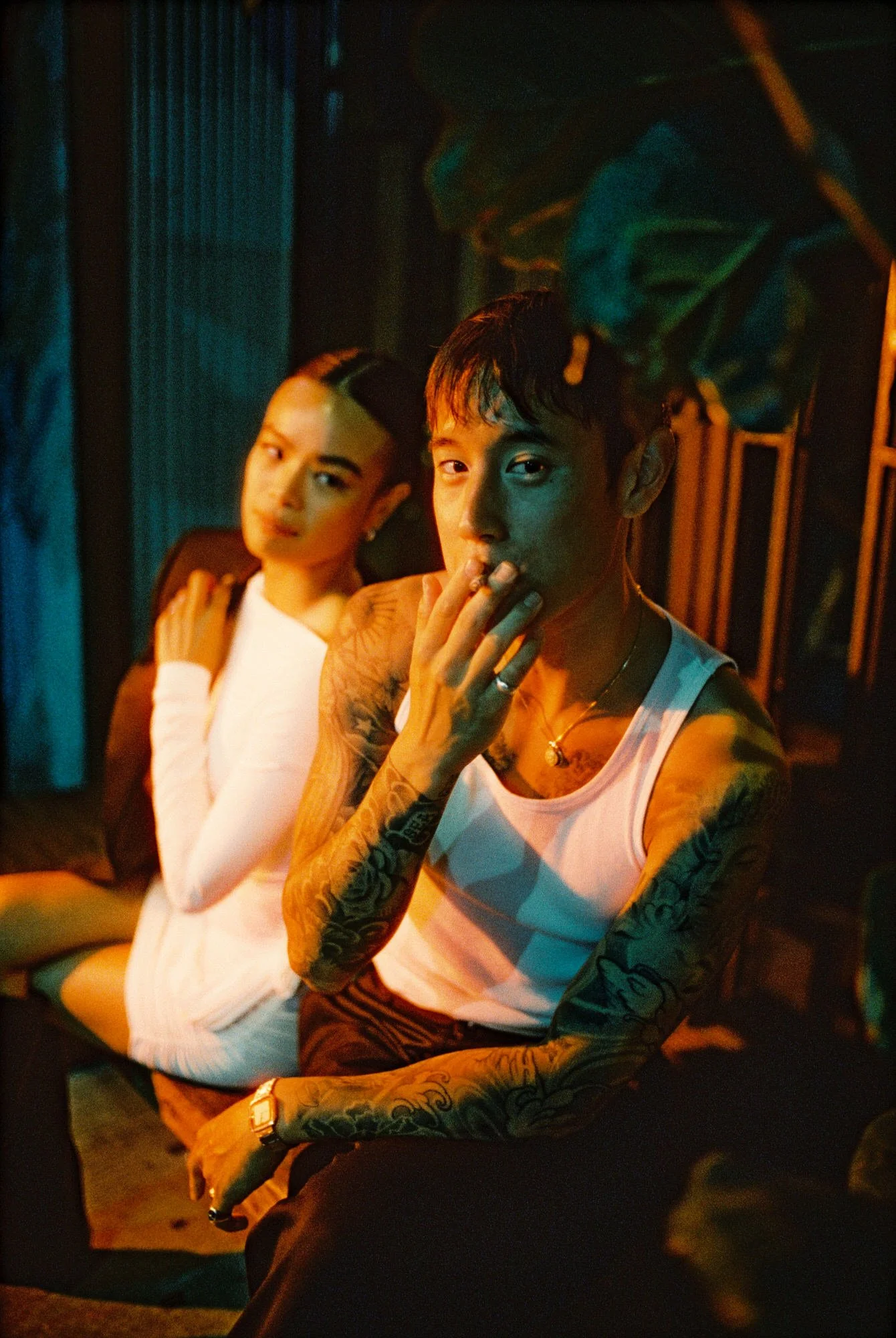 Cinematic portrait of a couple sitting close together under warm light in a Wong Kar-Wai inspired Chinatown moment, photographed by Jenny Fu  shot on film.