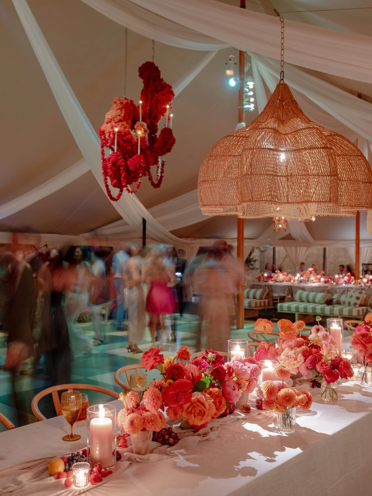 Candlelit reception table with vivid florals and red hanging chandelier as guests dance in the background at Valley Rock Inn in Sloatsburg, photographed by Jenny Fu.