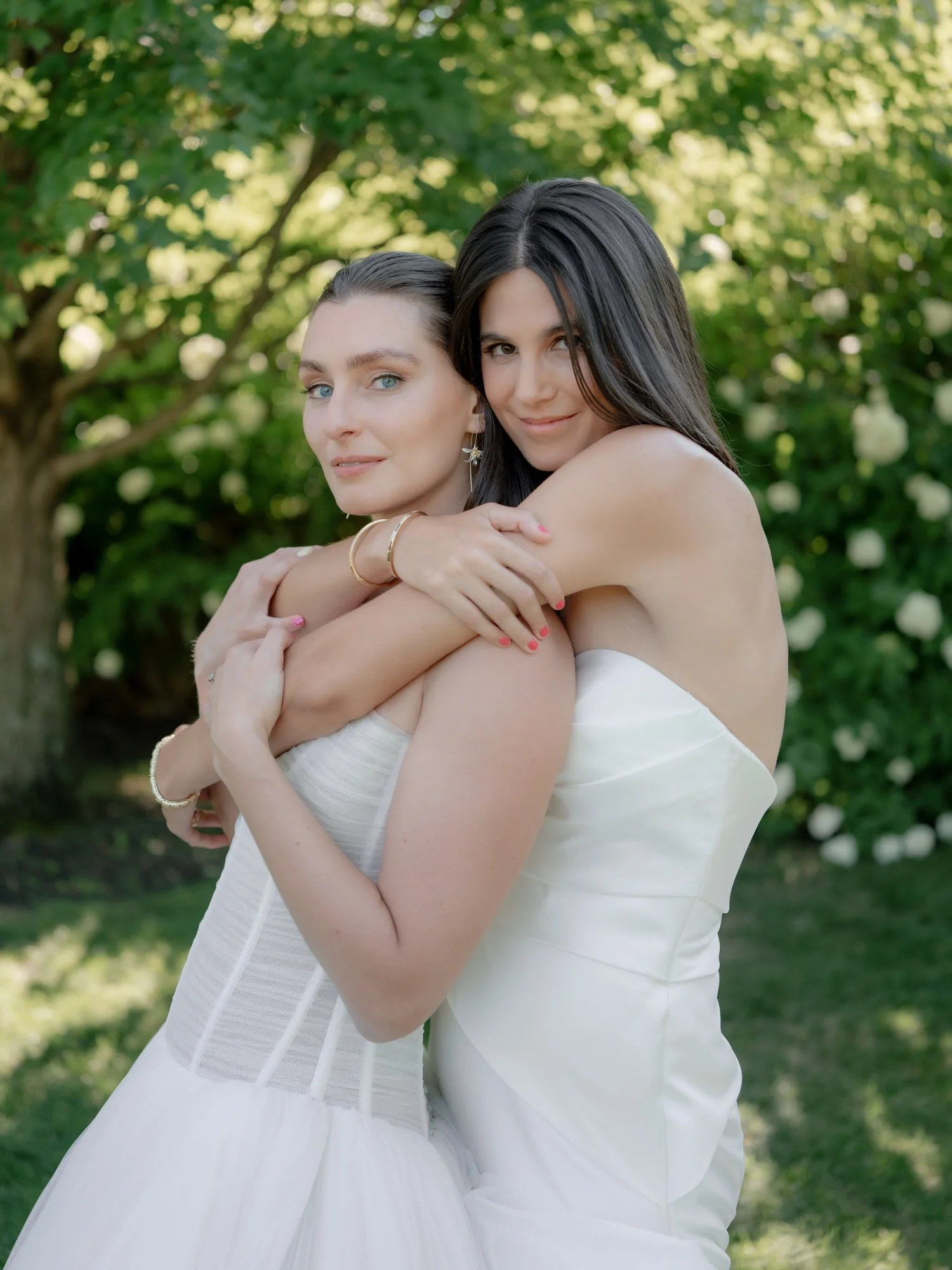 Brides sharing a quiet embrace in the garden at Valley Rock Inn, Sloatsburg, NY, photographed by Jenny Fu.