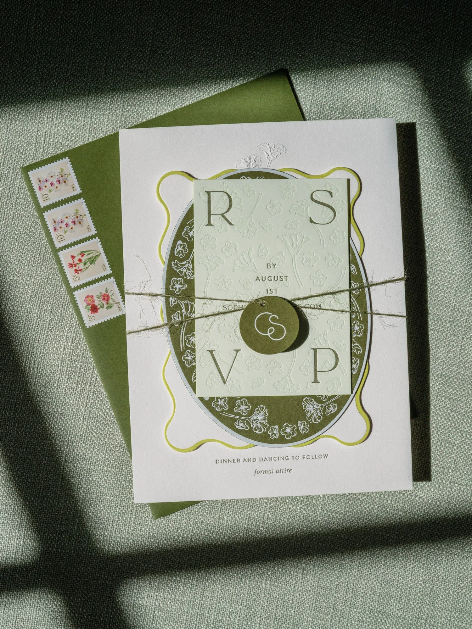Flatlay of embossed wedding RSVP with green envelope and floral stamps at Troutbeck in Amenia, photographed by Jenny Fu.