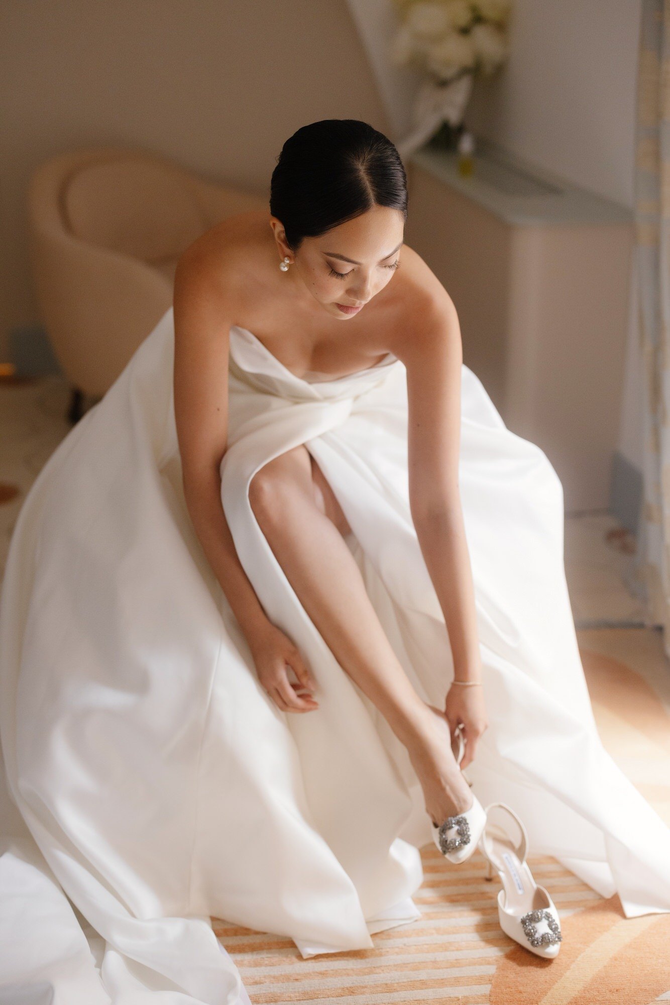 Bride adjusting her embellished heels while getting ready in her suite at Caruso, A Belmond Hotel in Ravello, Italy, photographed by Jenny Fu.