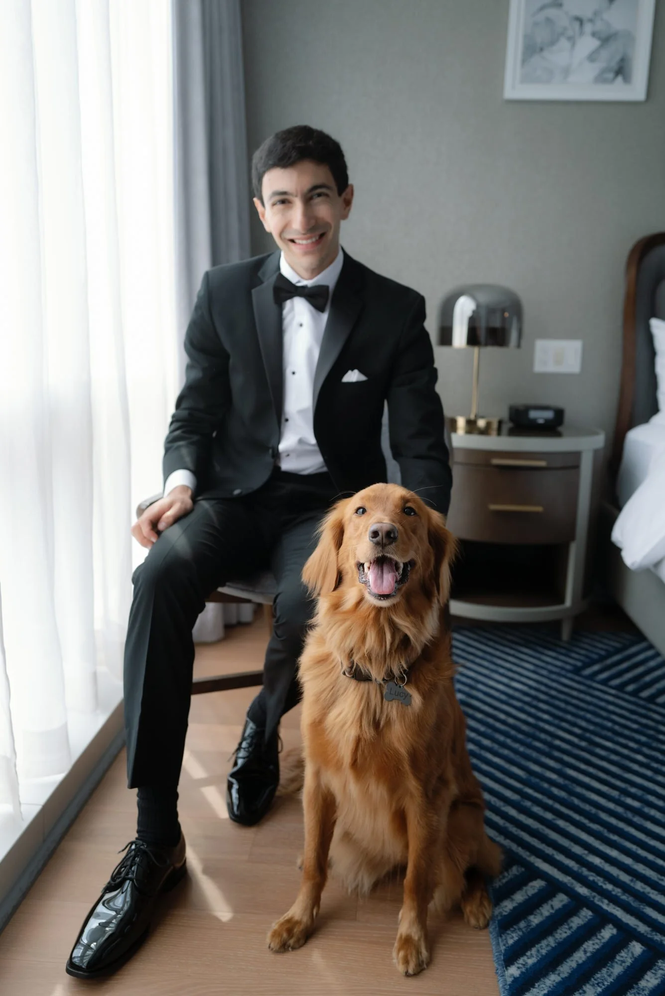 Groom seated by a window in a tuxedo with his golden retriever during a quiet getting ready moment at Blue Hill at Stone Barns, photographed by Jenny Fu.