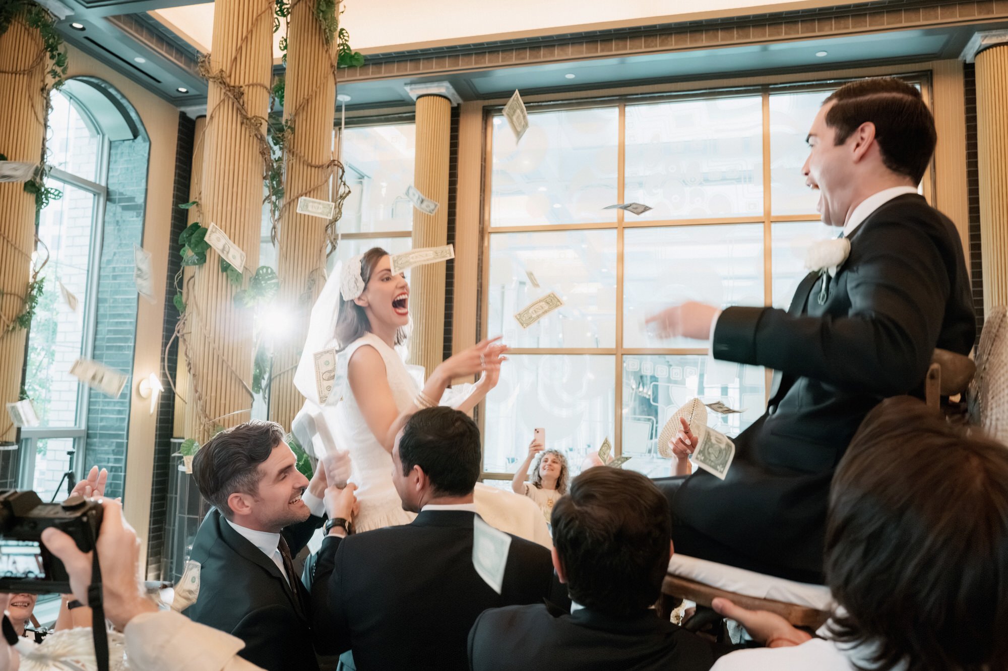 Groom lifted high on a chair above cheering guests at a Waldorf Astoria New York wedding reception, photographed by Jenny Fu.