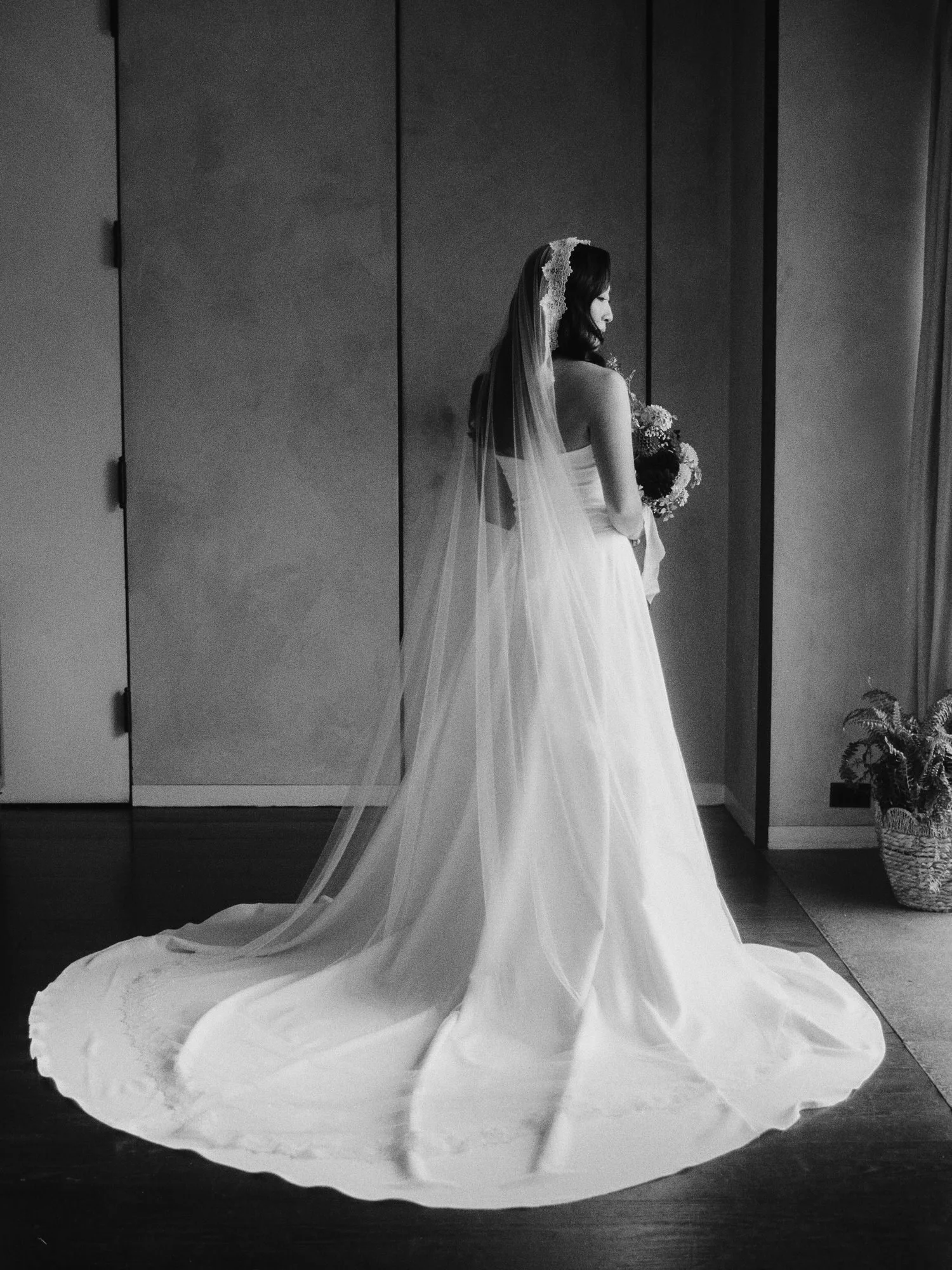 Black and white bridal portrait with cathedral veil and sweeping train by the window at Blue Hill at Stone Barns, photographed by Jenny Fu.