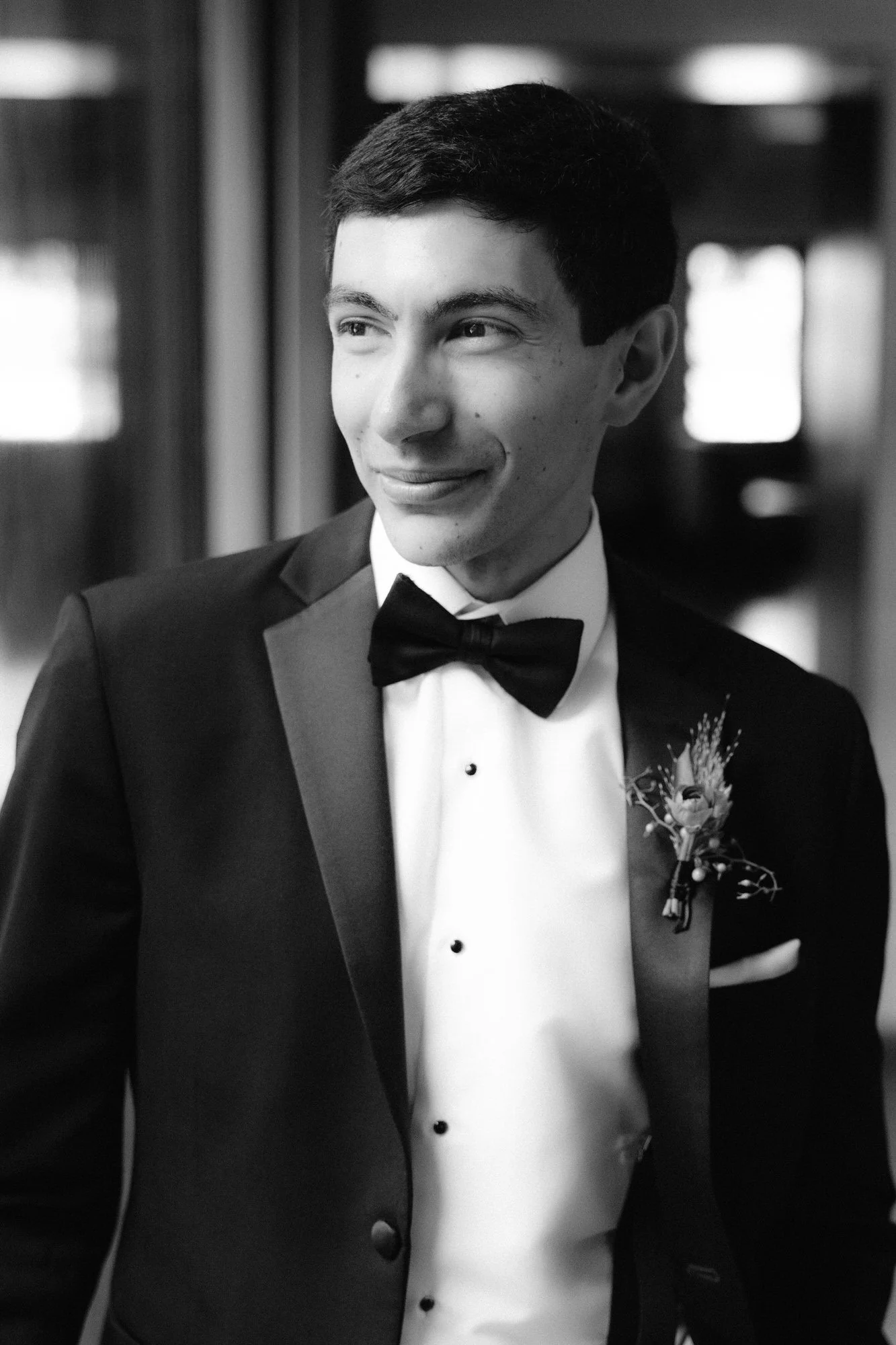 Black and white portrait of the groom in a classic tuxedo with a boutonnière, softly lit indoors at Blue Hill at Stone Barns, photographed by Jenny Fu.
