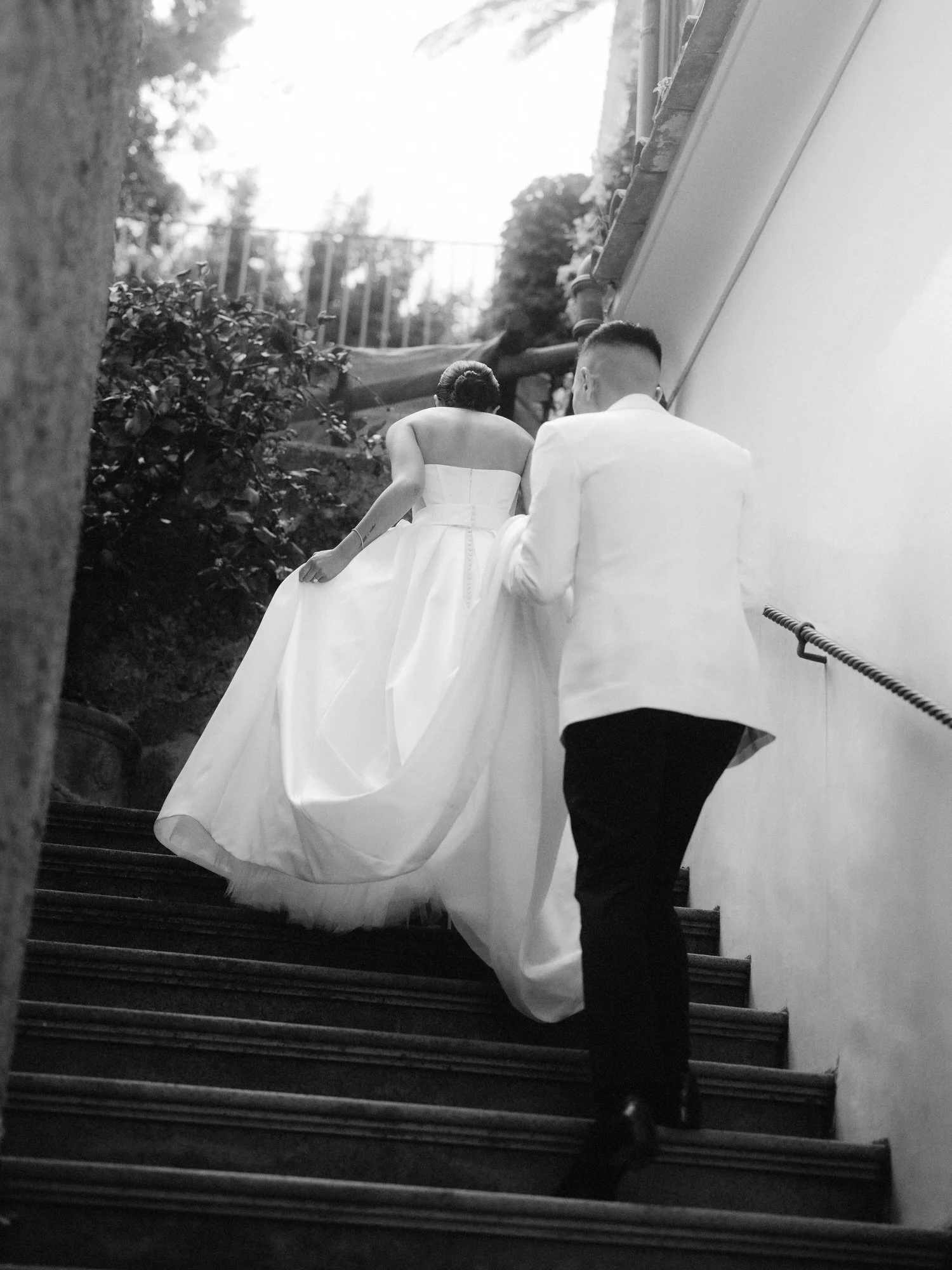 Bride and groom walking up a stone staircase together at Caruso, A Belmond Hotel in Ravello, Italy, photographed by Jenny Fu.