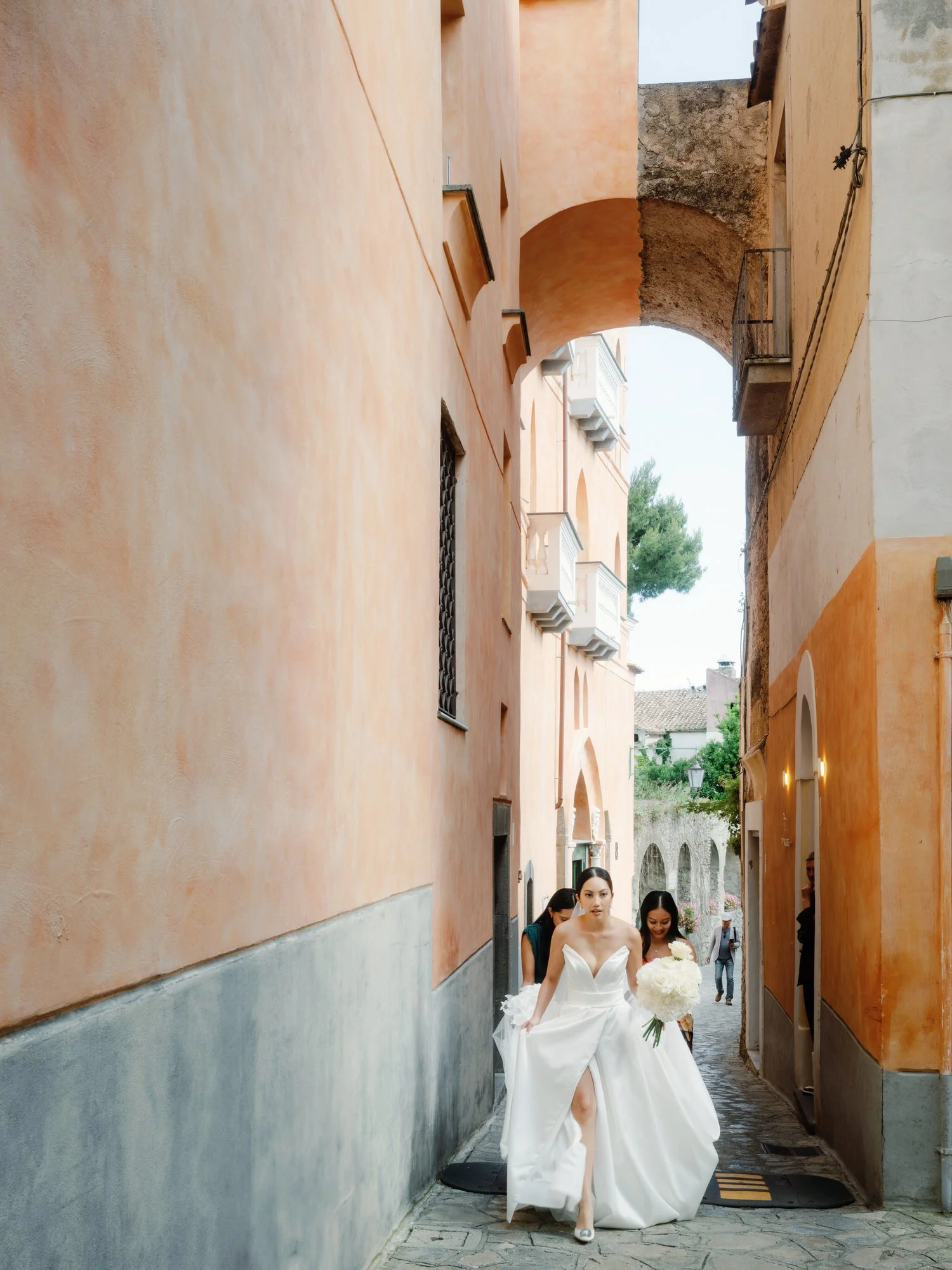 Bride walking through the narrow pastel alleyways of Ravello on her way to the ceremony at Caruso, A Belmond Hotel, photographed by Jenny Fu.