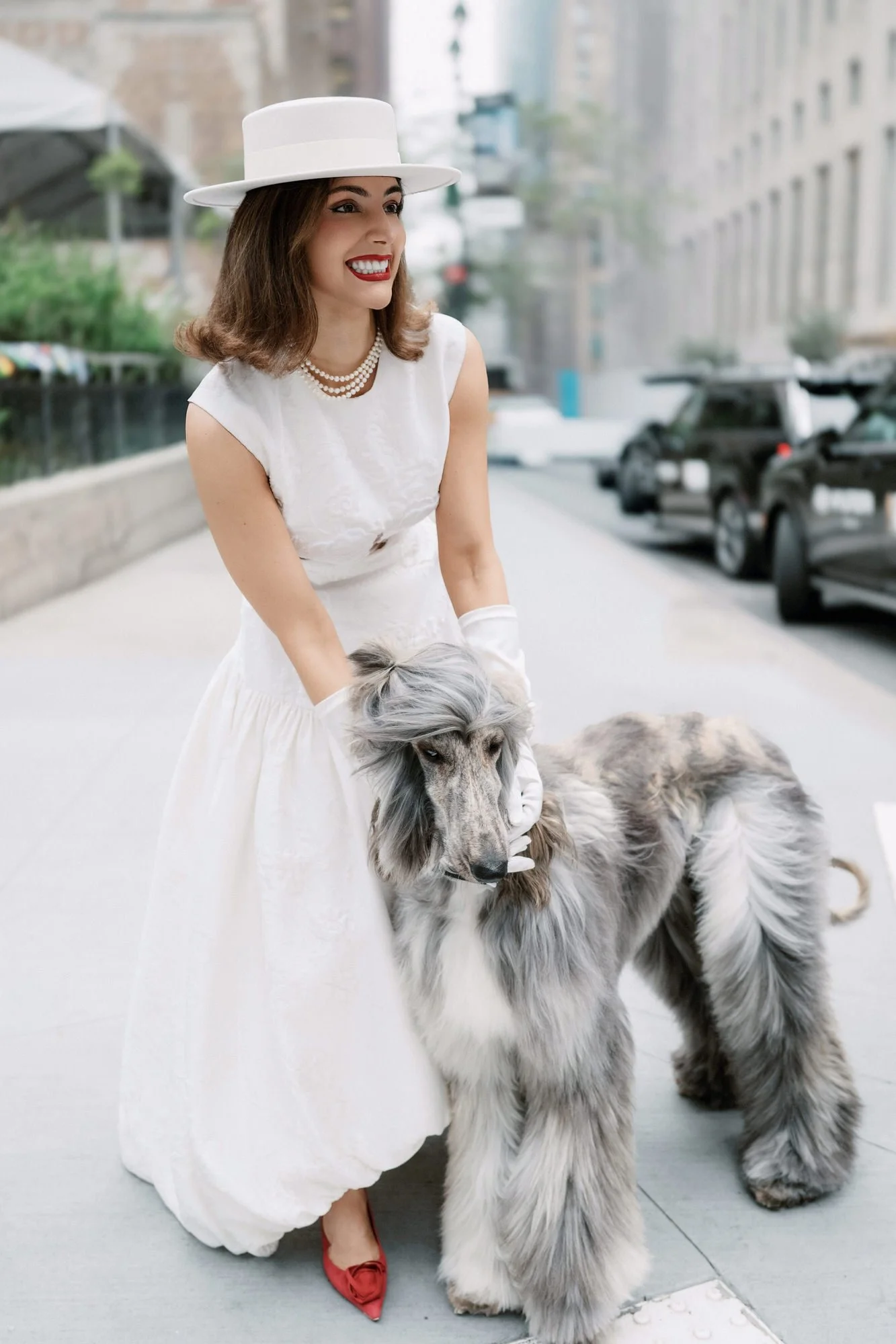 Stylish bride in a white boater hat and gloves walking her Afghan hound outside the Waldorf Astoria New York, photographed by Jenny Fu.